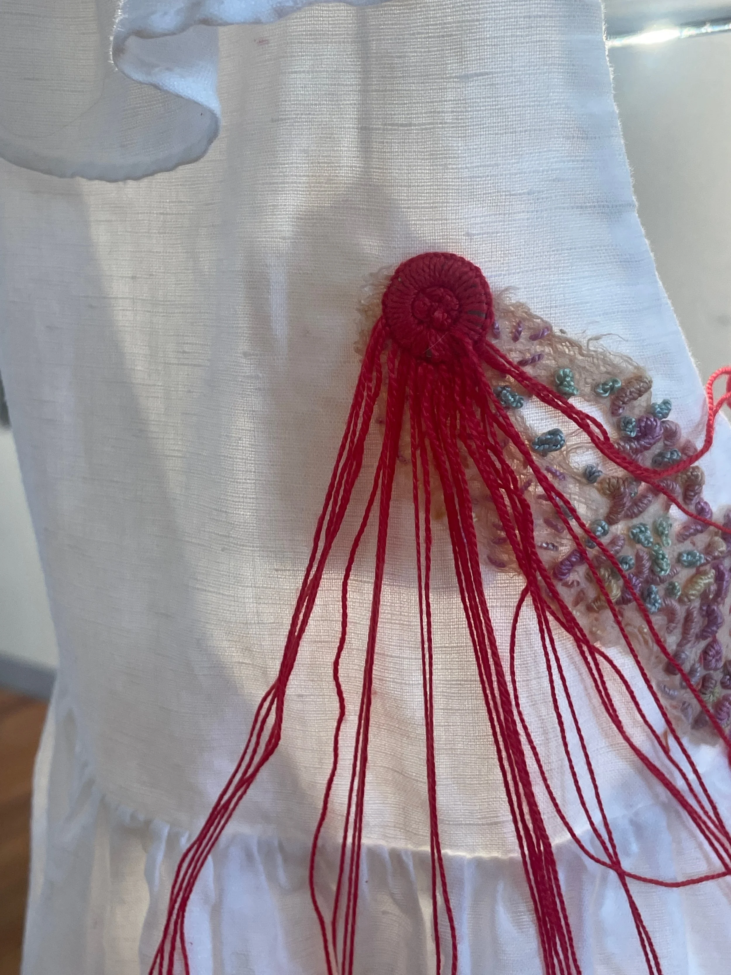 Here begins the cutting board of shape making…, 2026. Improvisational
embroidery on granddaughter’s discarded white frock. Photograph Joy Denise Scott