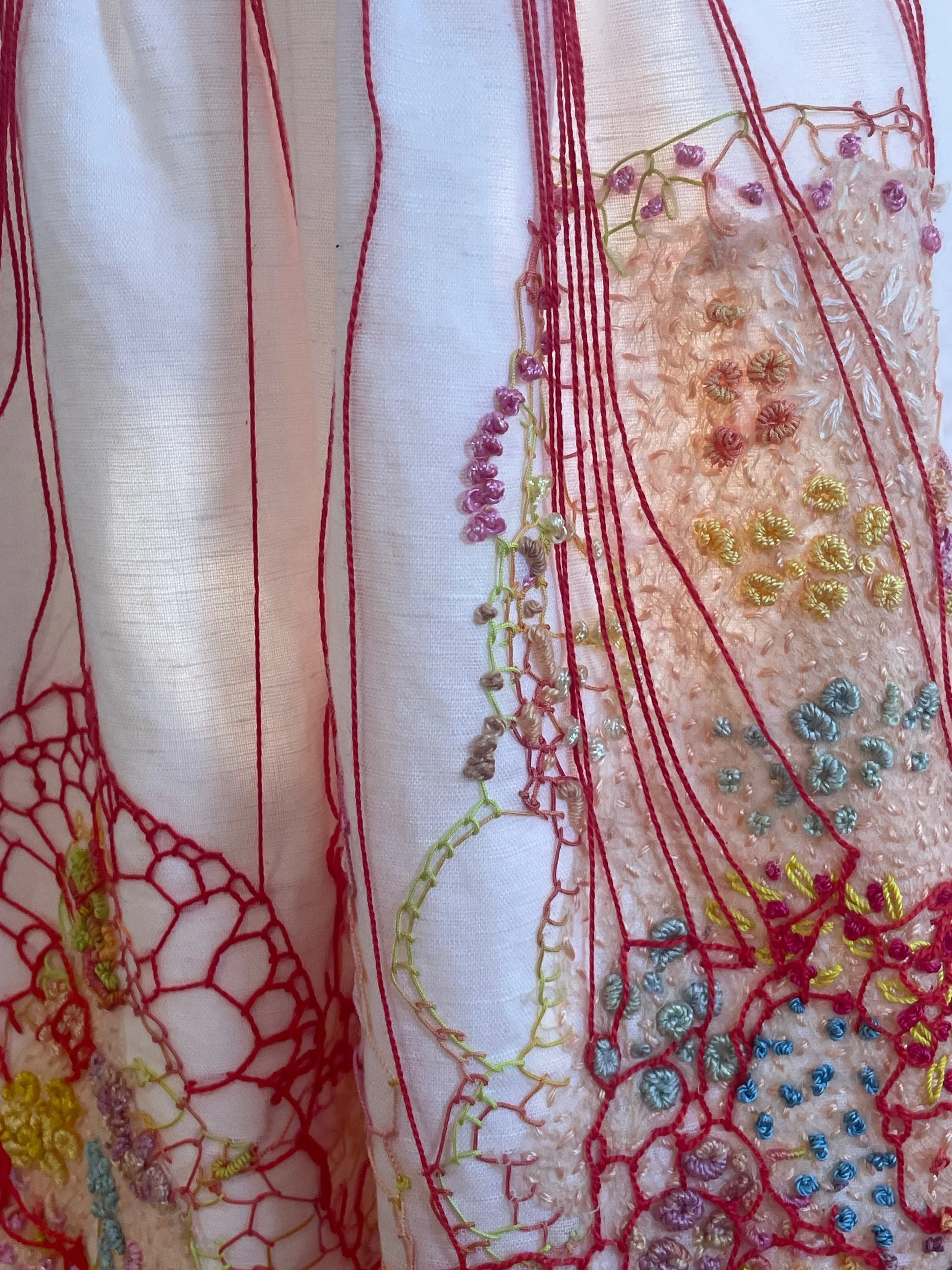 Here begins the cutting board of shape making…, 2026. Improvisational
embroidery on granddaughter’s discarded white frock. Photograph Joy Denise Scott