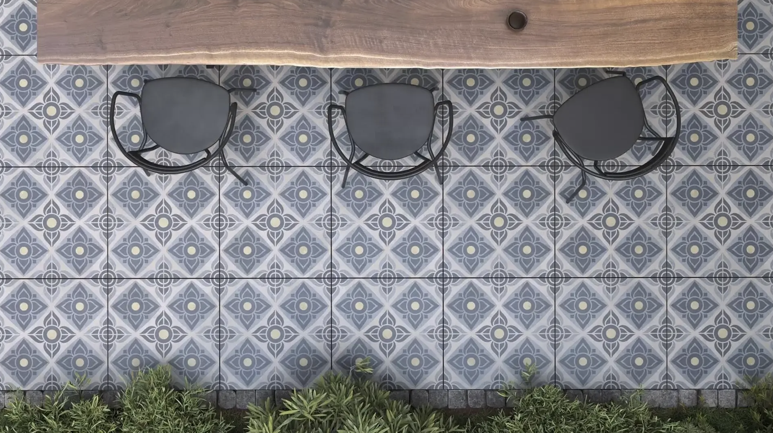 Kolme mustaa tuolia ja kasveja lattian reunassa, katonäkymä