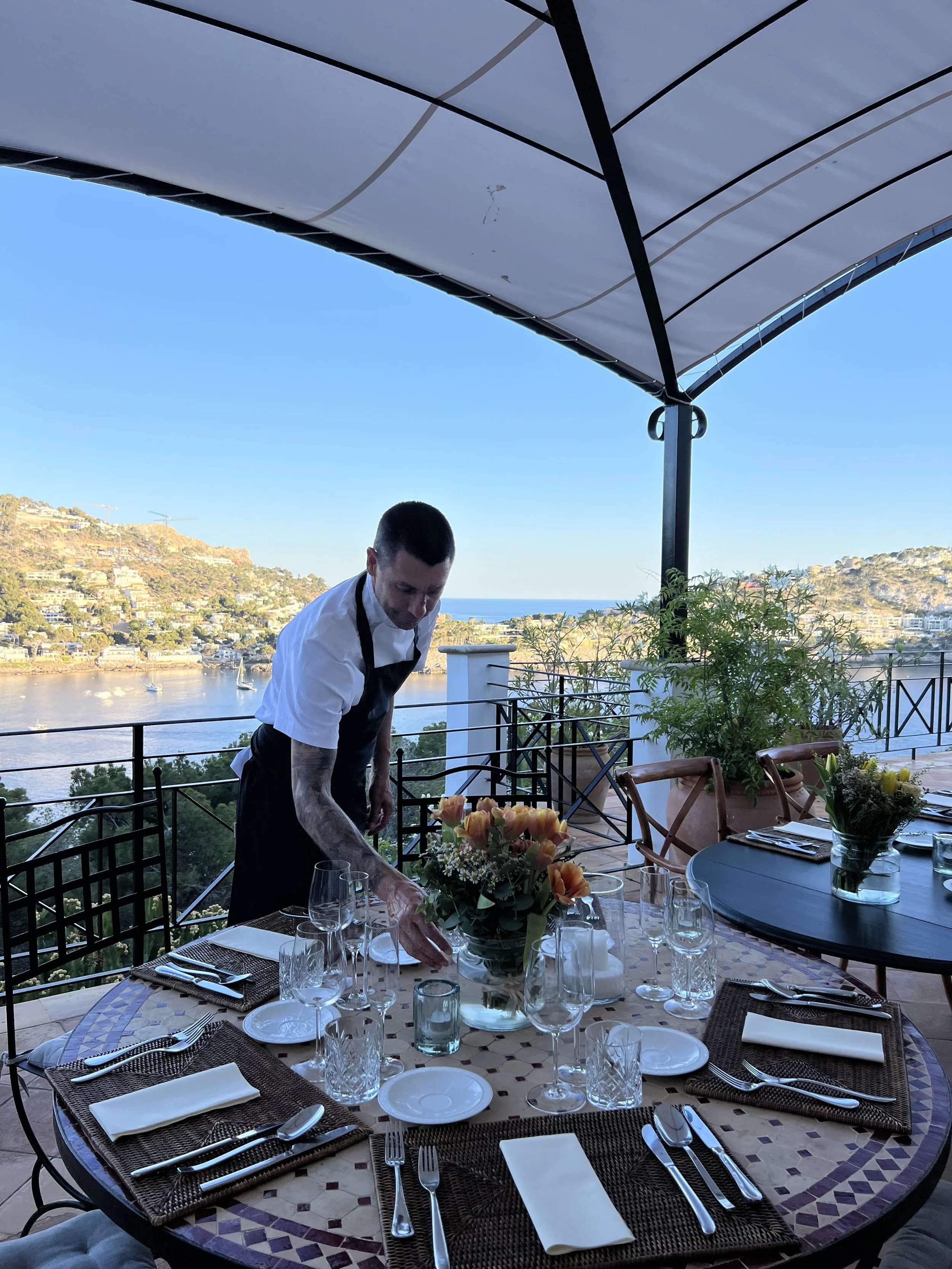 Private chef in Mallorca setting up a luxury dining table on a villa terrace with sea views