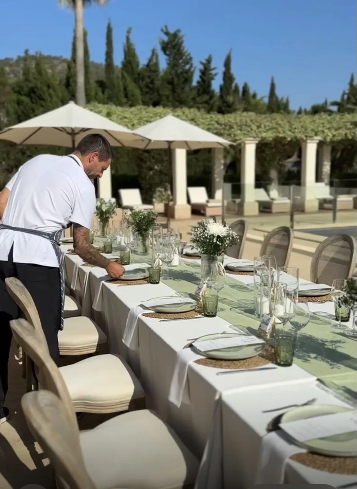Private chef in Mallorca setting up an elegant outdoor villa dining table by the pool