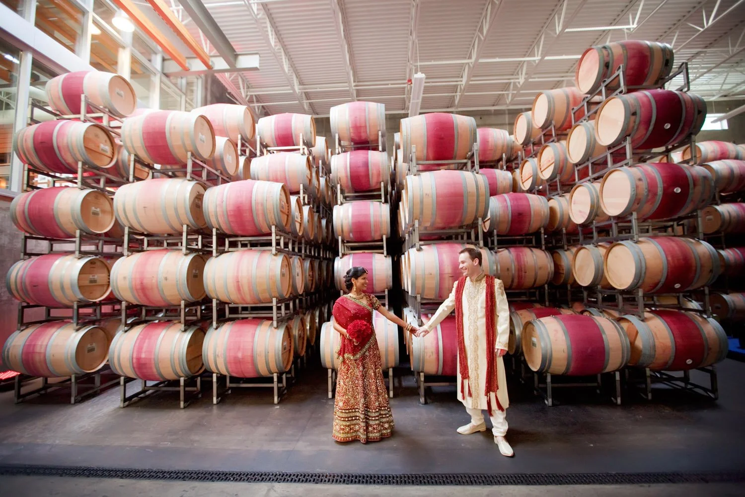 A bride in groom portrait in their red and gold Indian attire in front of wine barrels at the Novelty Hill-Januik Winery-Photography by Jaime Hammond Photography -planned and designed by Simply Wed