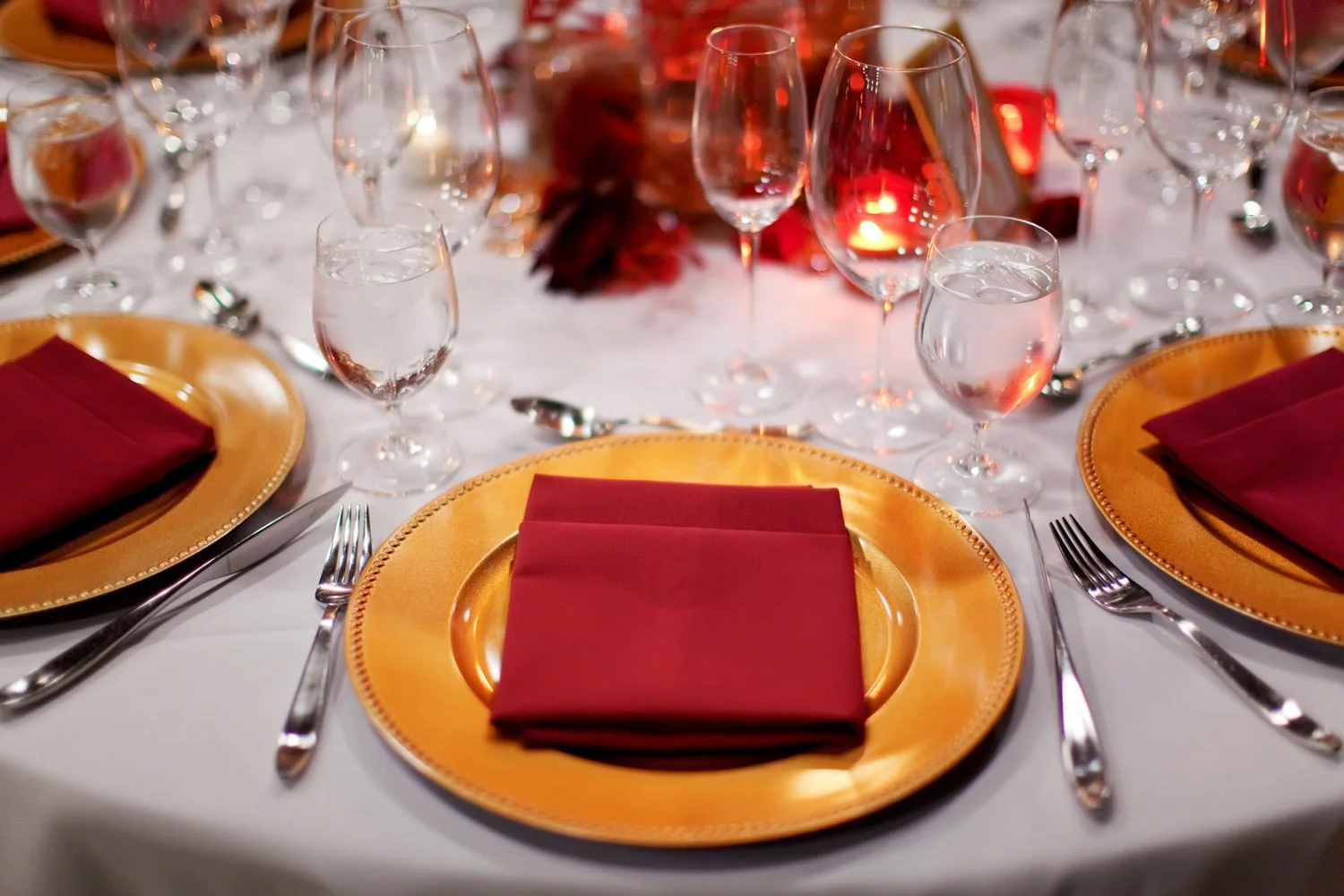 Gold plates with red napkins and crystal glassware lit by candlelight at the Novelty Hill-Januik Winery-Photography by Jaime Hammond Photography -planned and designed by Simply Wed