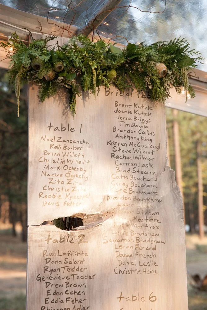 A piece of smooth wood with all the wedding table settings written out in handwriting. A lovely 'on theme' touch designed by Simply Wed.