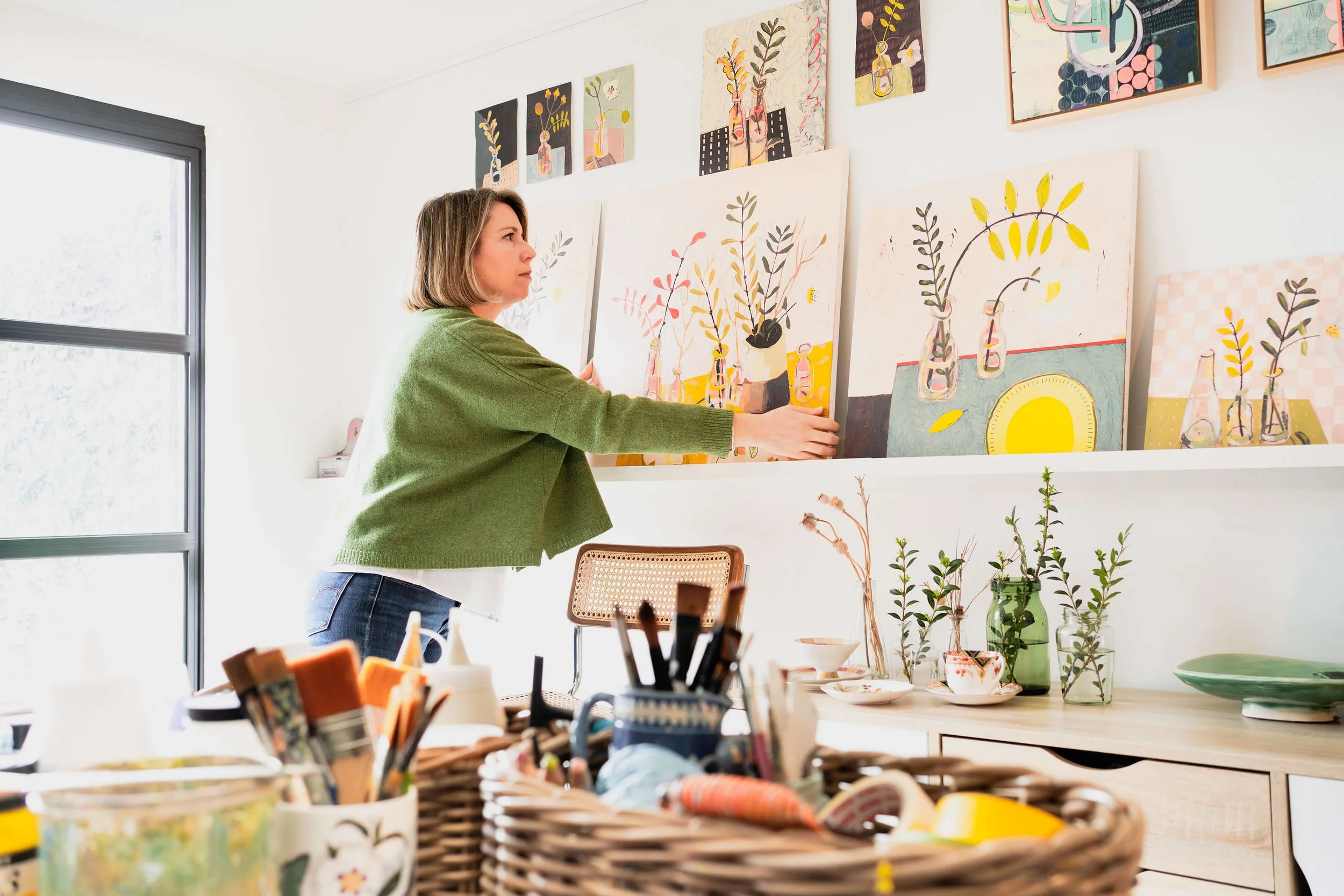 Ali Mackie is the gallery manager smiling surrounded by art at Emerald Frames and Art Gallery