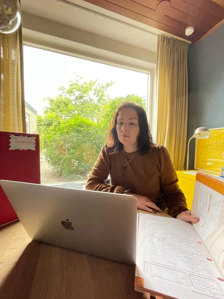 Female English teacher working from home on her computer with english language learning books open