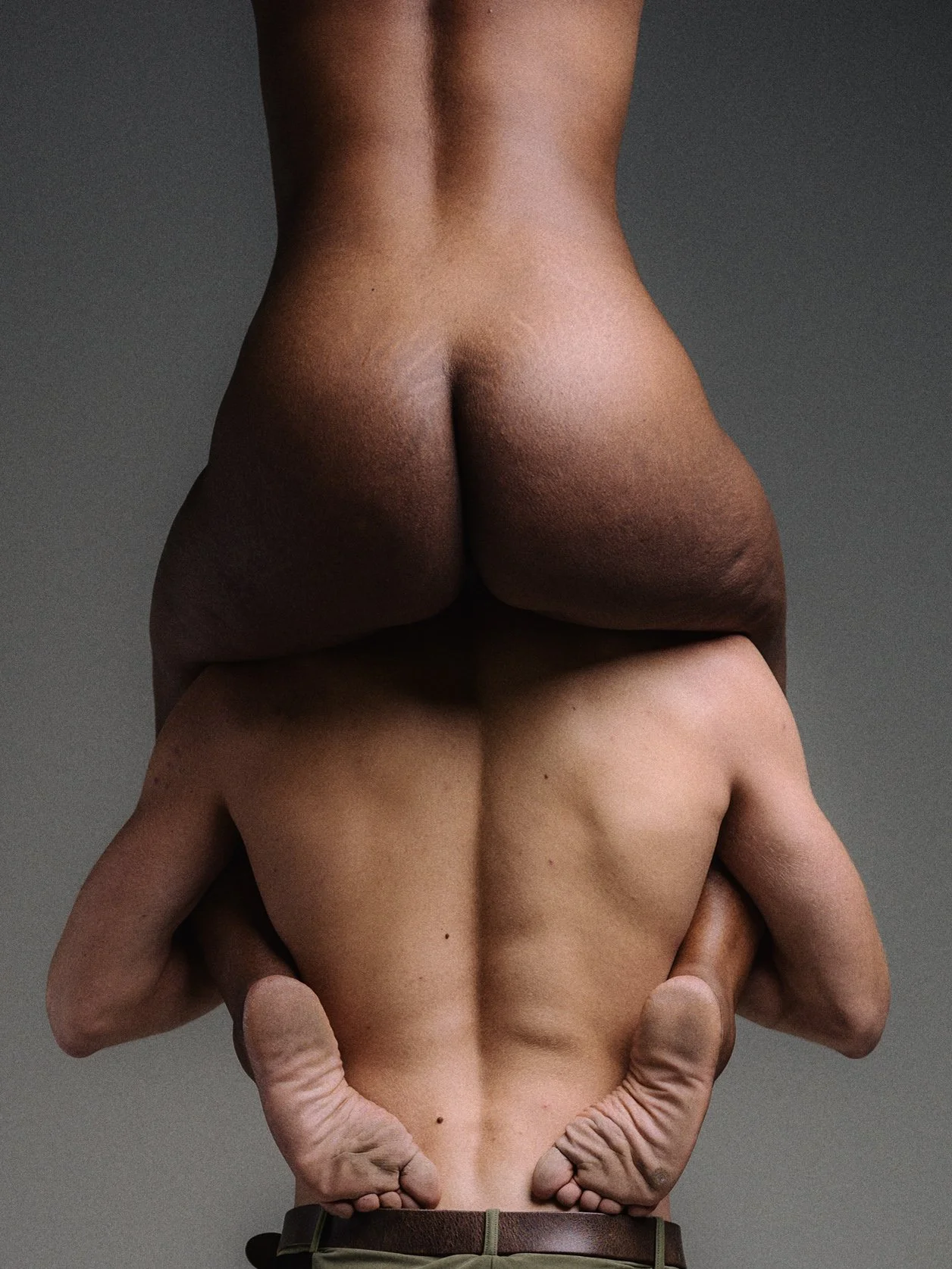 Natuurlijk naakte persoon die op hun buik ligt, onderste functie met hun armen achter hun hoofd in een gestileerde pose.