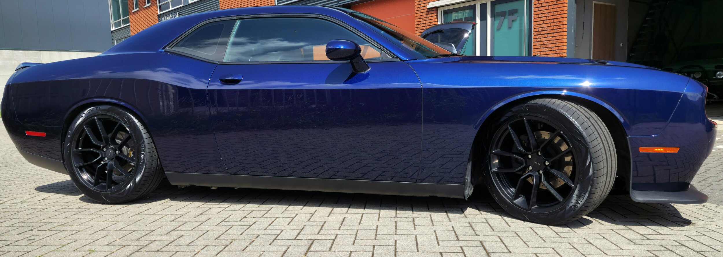 Blauwe sportwagen op een parkeerplaats, zijaanzicht