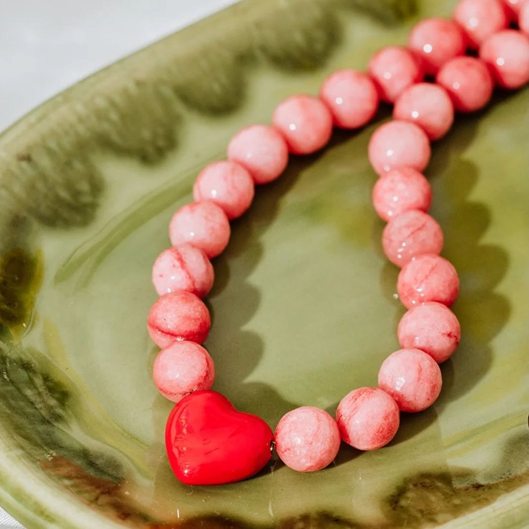 Meet Bonnie! Her name inspired by the bon bon sweets. A playful yet romantic piece designed to bring warmth and personality to your everyday style. Faceted pink jade beads are paired with a bold red heart pendant, creating a joyful colour-clash that 