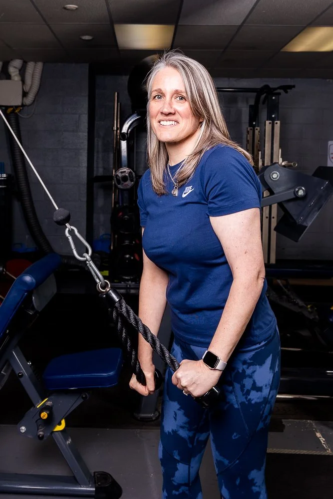 Woman in blue athletic wear exercising with a cable machine in a gym.