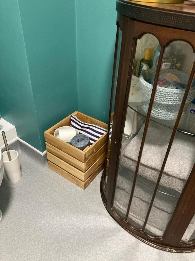 Wooden box on floor with green wall and wooden cabinet