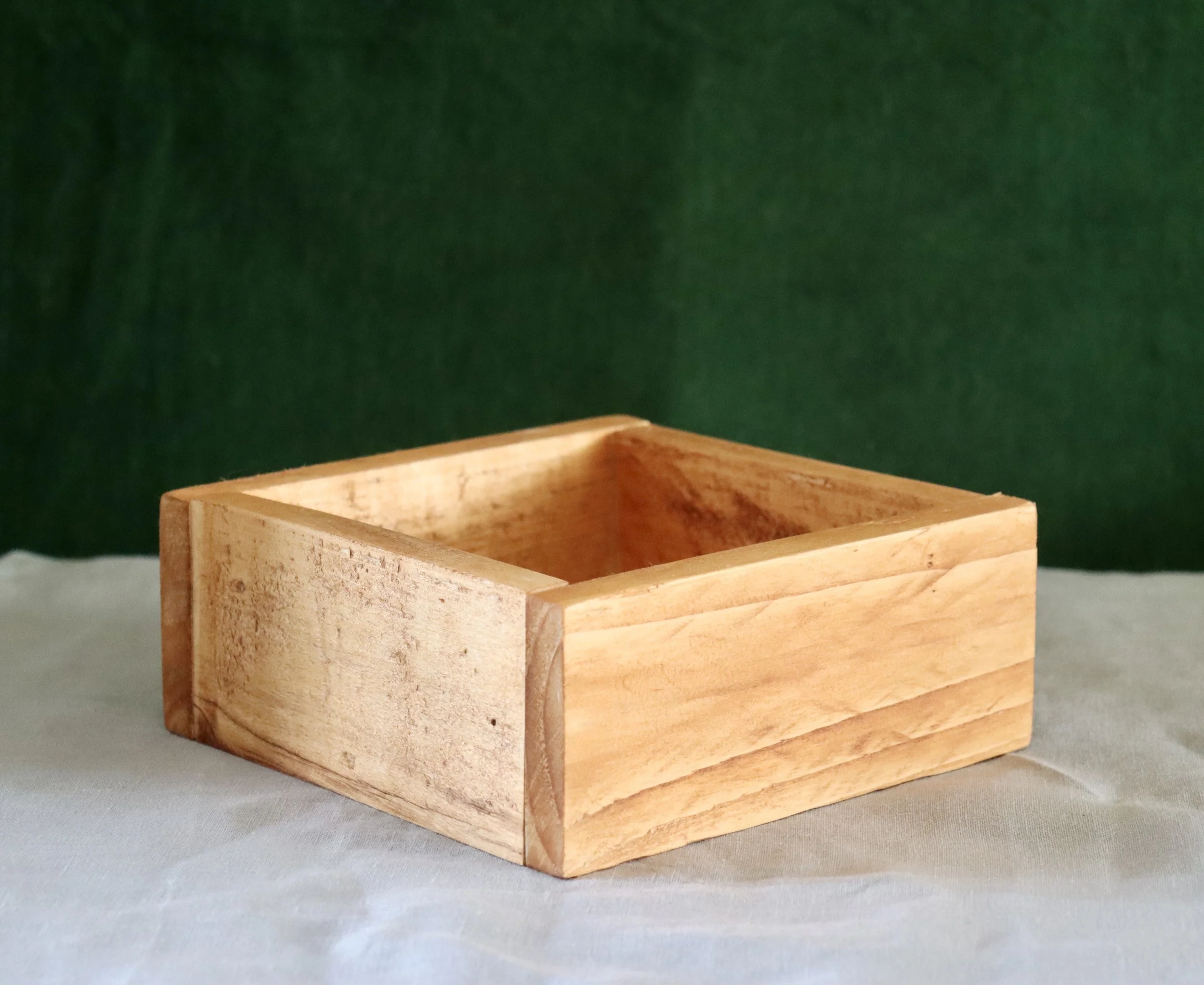 Wooden box on cream table and green background