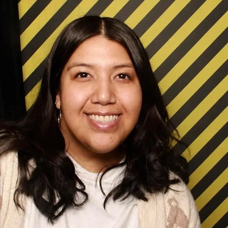 A smiling young woman in front of a black and yellow striped background