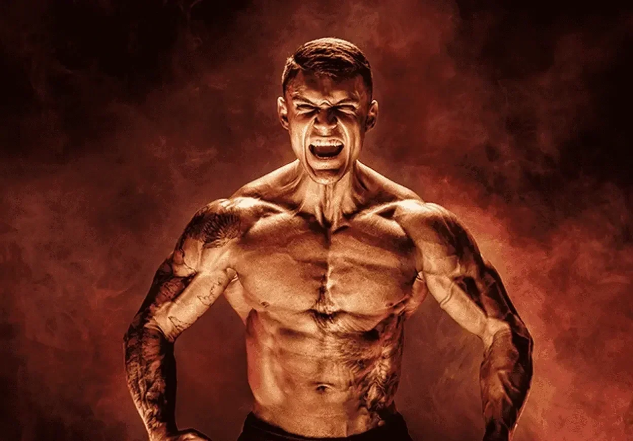 An extremely muscular shirtless man with tattoos on his arms and shoulders, yelling with an intense expression, set against a dark fiery background.