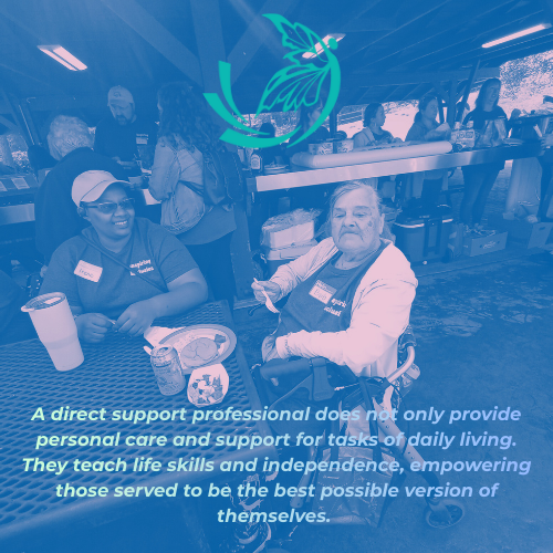 Two women smiling and sitting at a table with drinks and food in a social setting, with other people in the background.