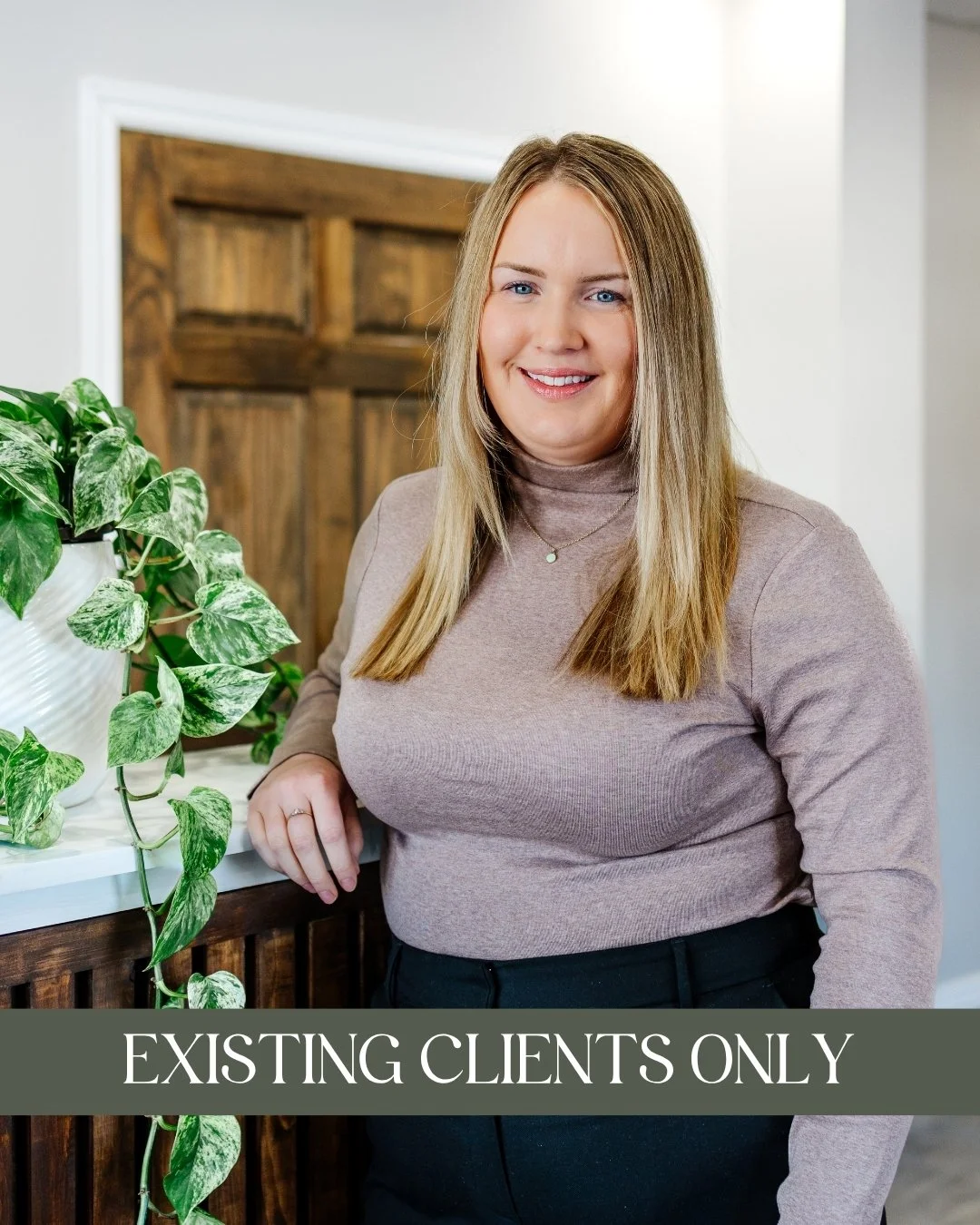 Jodie English, MSW, RSW - A smiling woman with blonde hair, wearing a light pink turtleneck and black pants, and leaning on a wooden counter with a green leafy plant nearby and a caption that reads "Accepting New Clients."