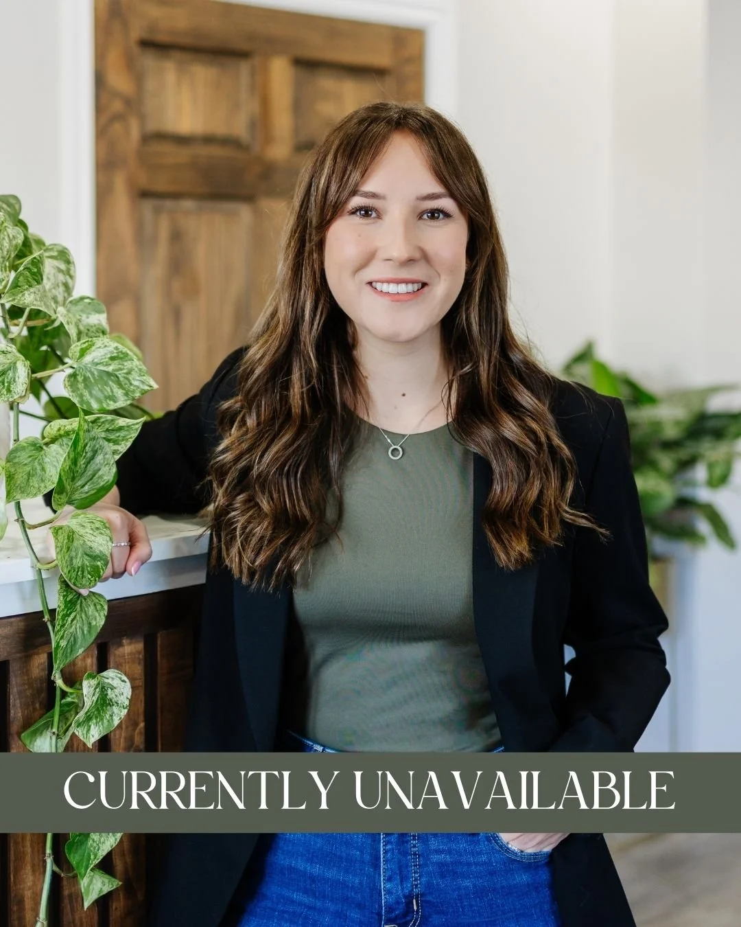 Olivia Krysinski, RP (Qualifying) - A smiling woman with long brown hair, wearing a black blazer over a green top, and leaning on a wooden counter with a green leafy plant nearby and a caption that reads "Currently Unavailable."