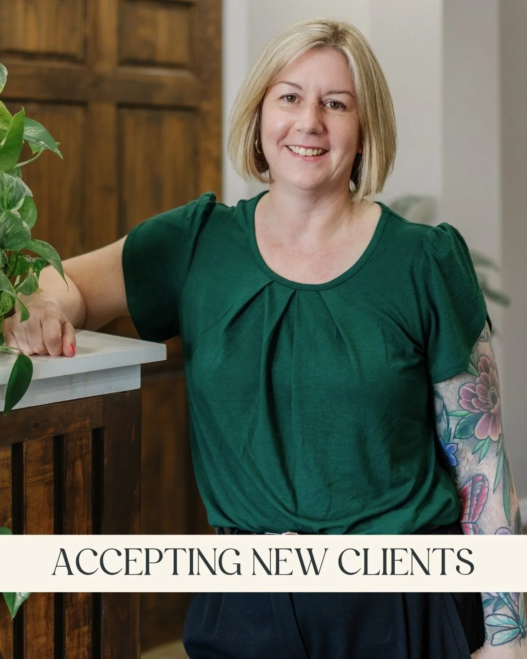Laura Wood, RP (Qualifying) - A smiling woman with brown hair, wearing a gray vest and white long-sleeve shirt, and leaning on a wooden counter with a green leafy plant nearby and a caption that reads "Low-Cost Therapy, Accepting New Clients
