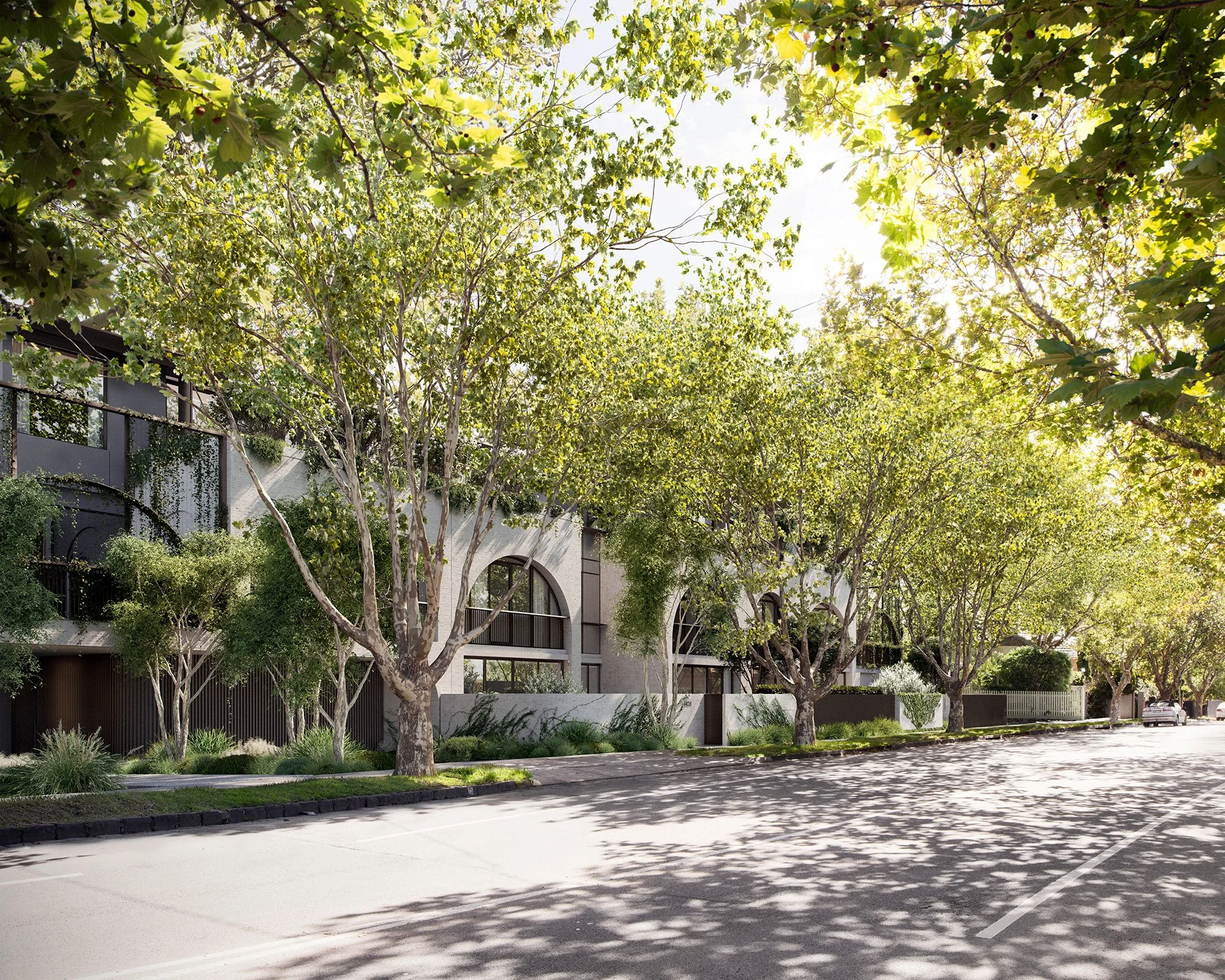 Street view of modern residential building with large trees and greenery along the sidewalk.