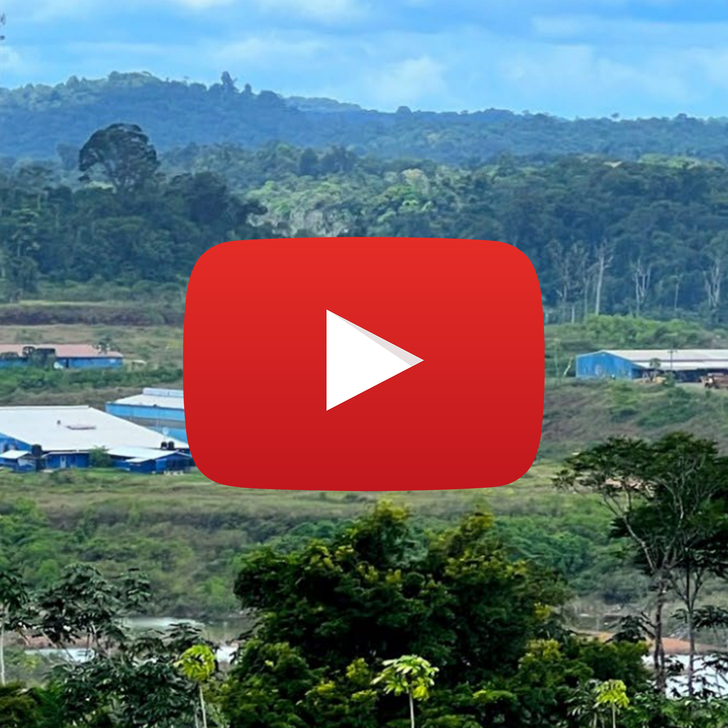 Scenic view of green hills, some buildings with blue roofs, and trees. Large YouTube play button overlay in the center.