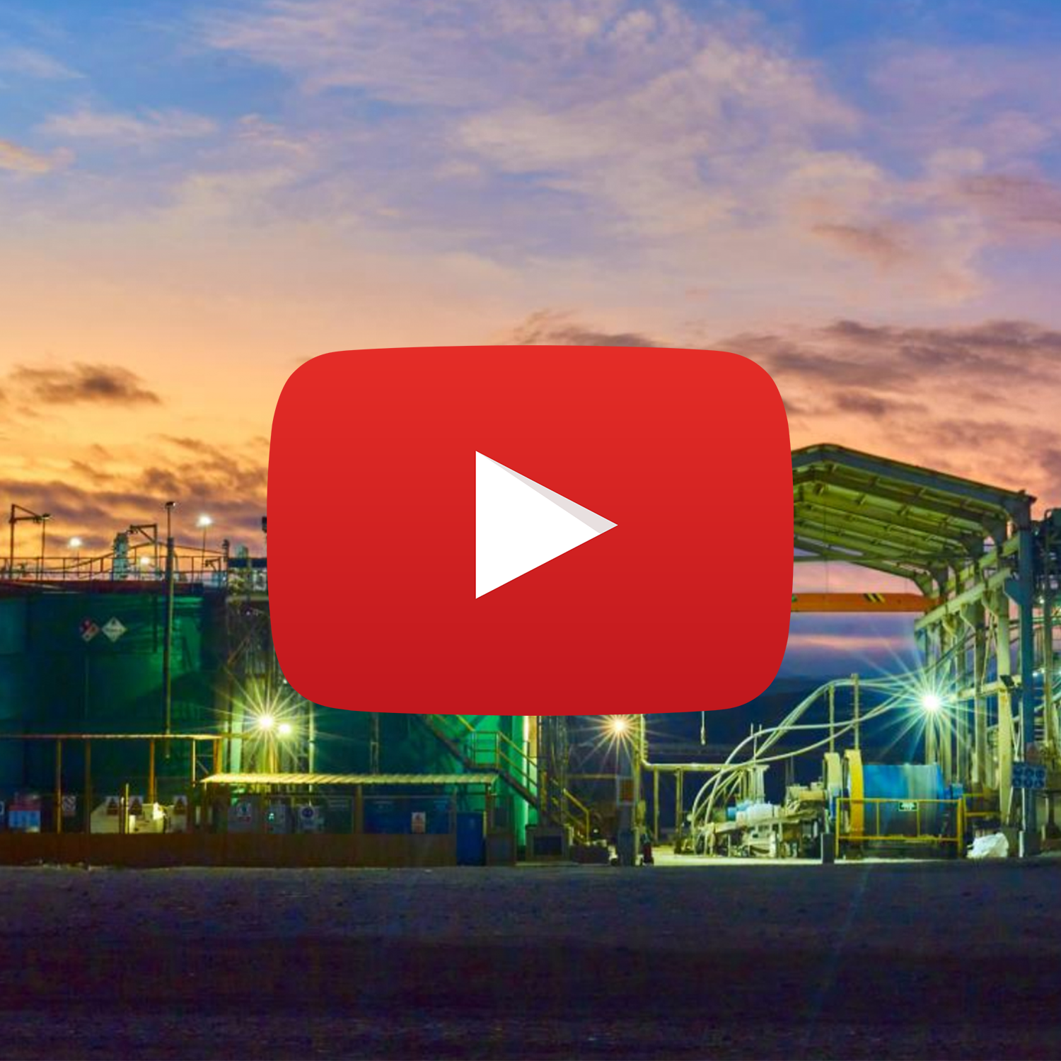 Industrial site at sunset with pipes, structures, and bright lights.