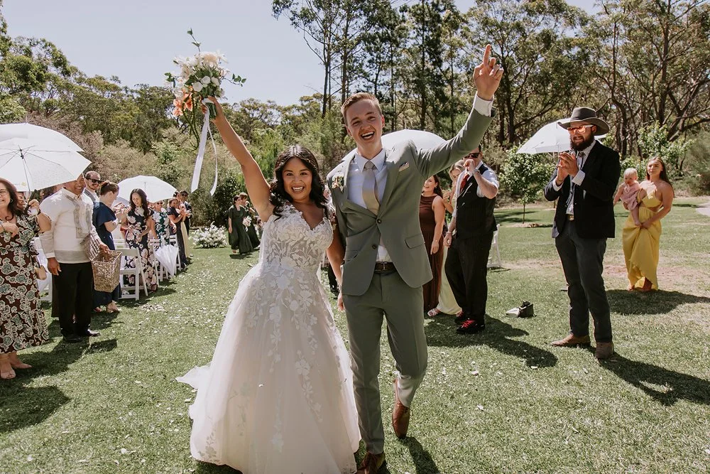Couple walking back up the aisle through a confetti tunnel in the Southern Highlands NSW