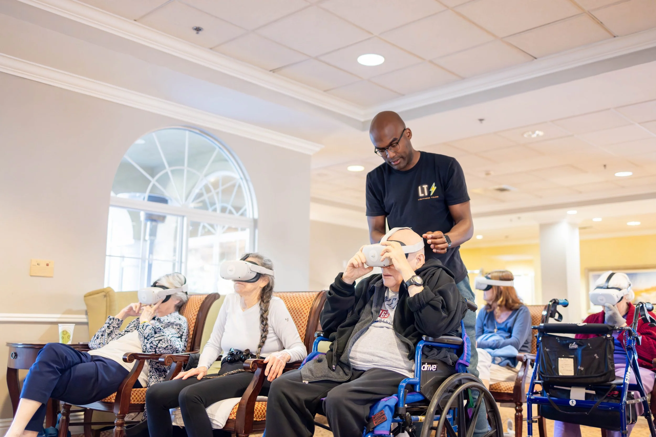 Lightning Tours team member assisting a resident with a VR headset during a group session