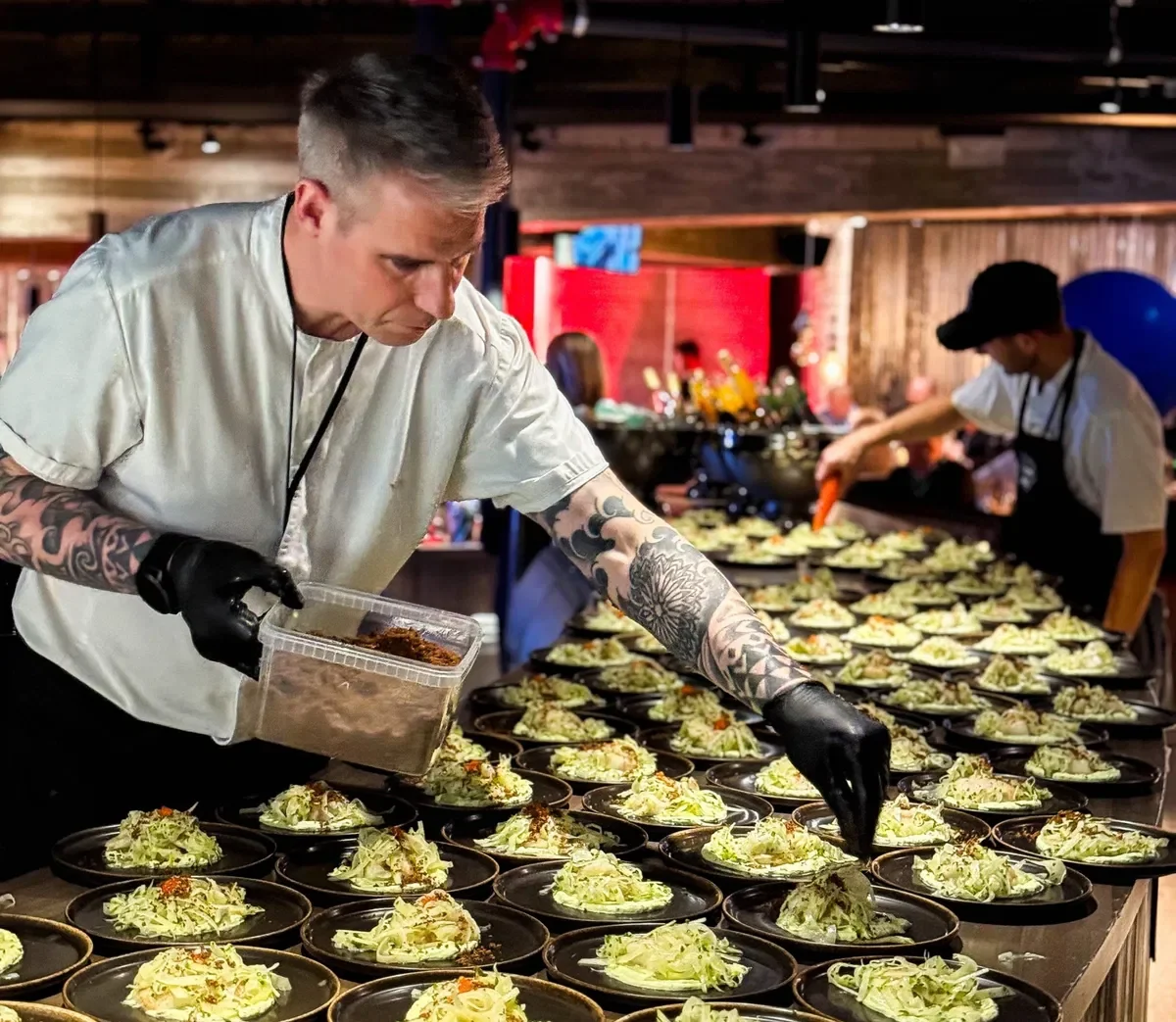 Kokk som legger på salatretter i en restaurant eller et arrangement.