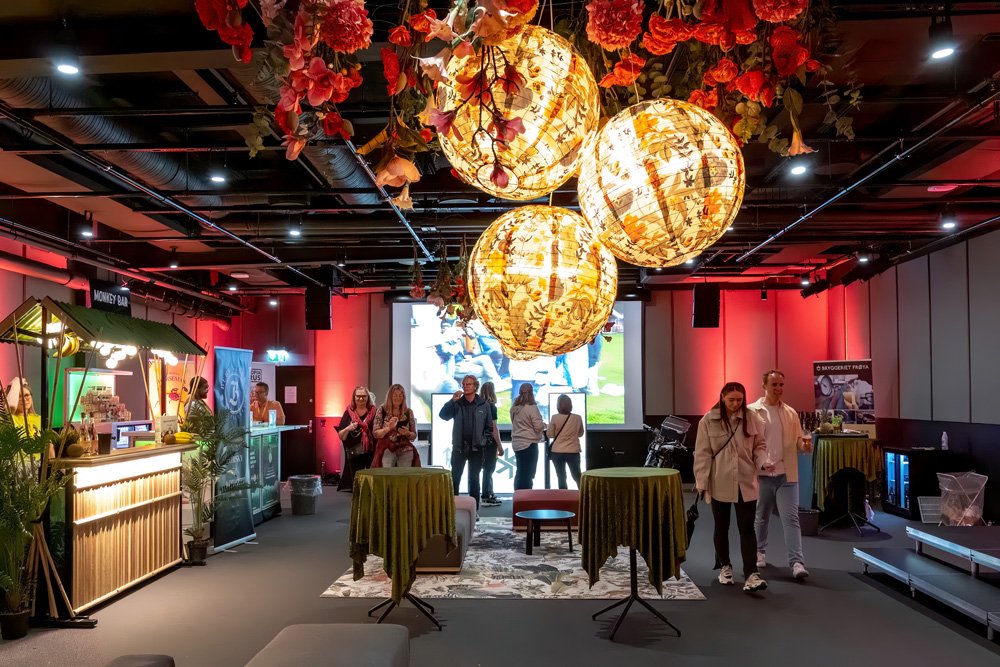 Indoor event venue with floral decorations, spherical light fixtures, and a bar area