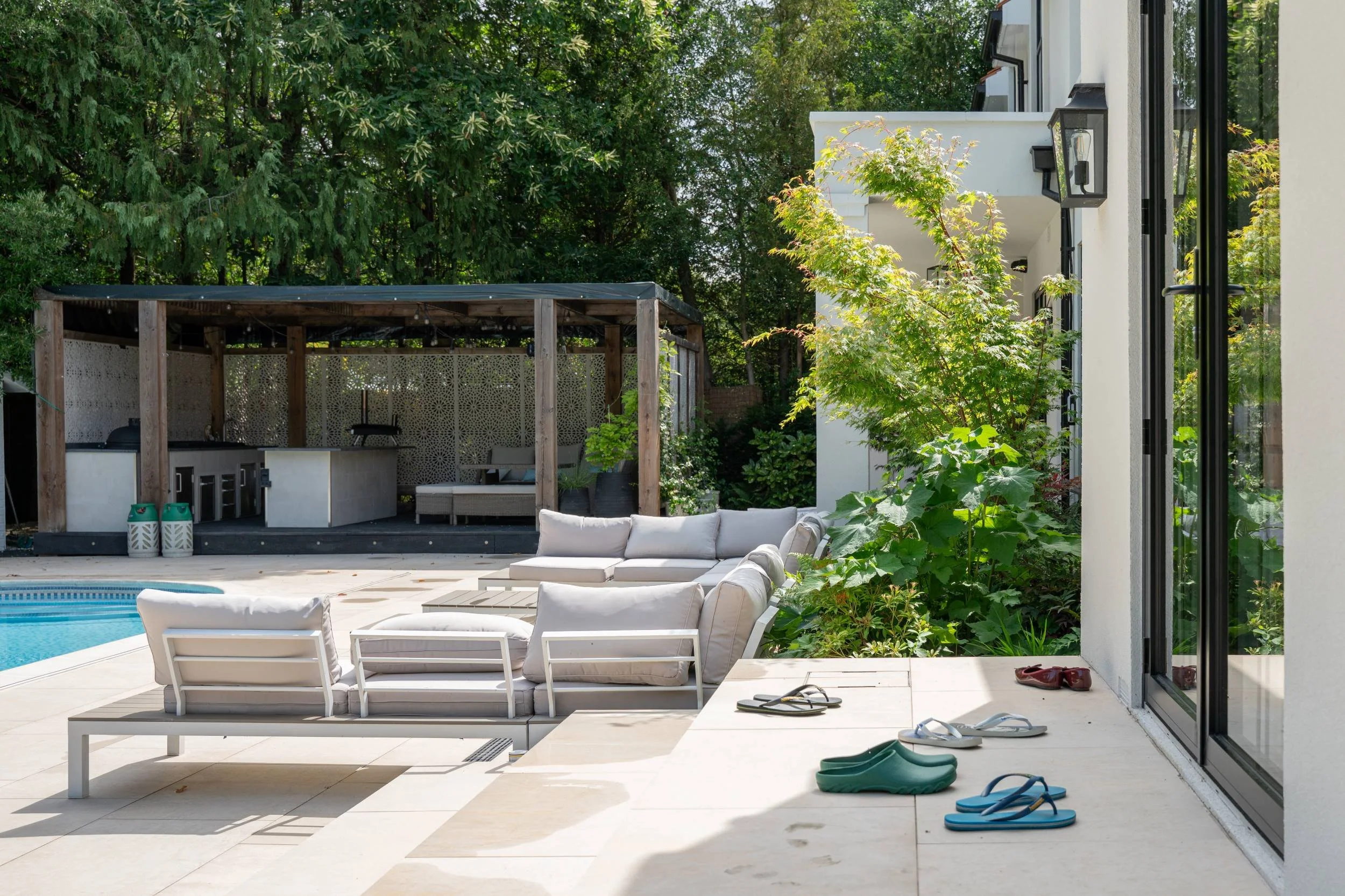 Covered seating area beside the pool in a Weybridge family garden designed by The Plant Hunter