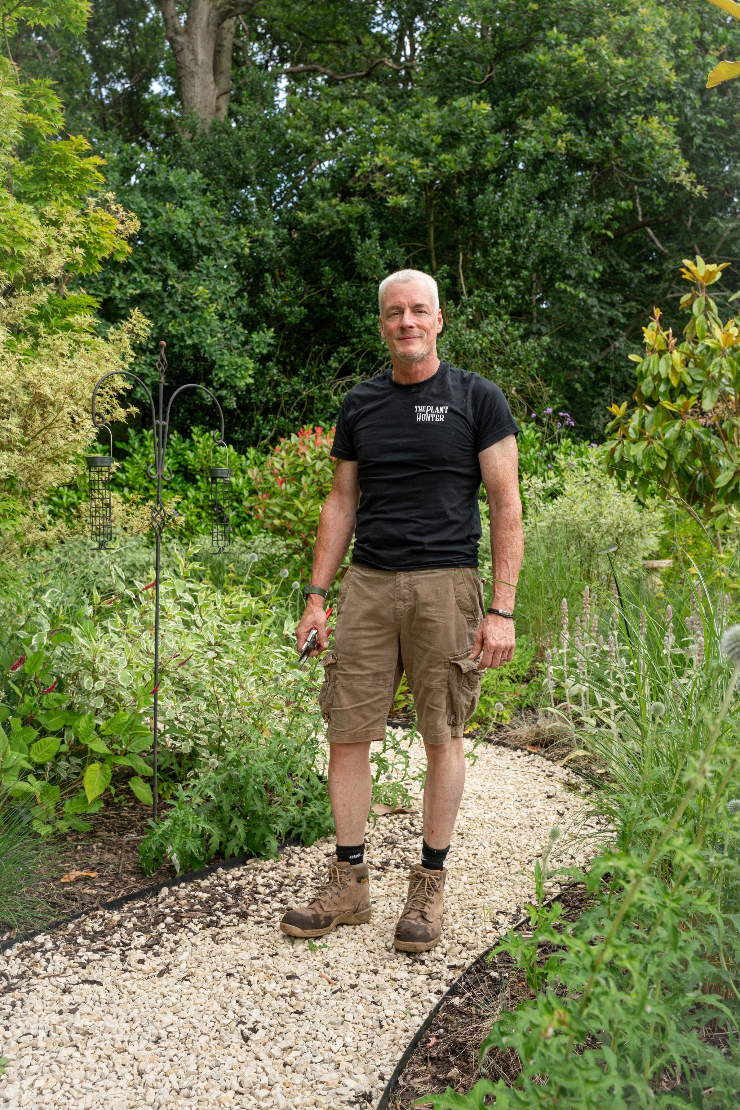 Paul Studholme, garden designer at The Plant Hunter, with secateurs on a gravel path in Cobham Surrey.