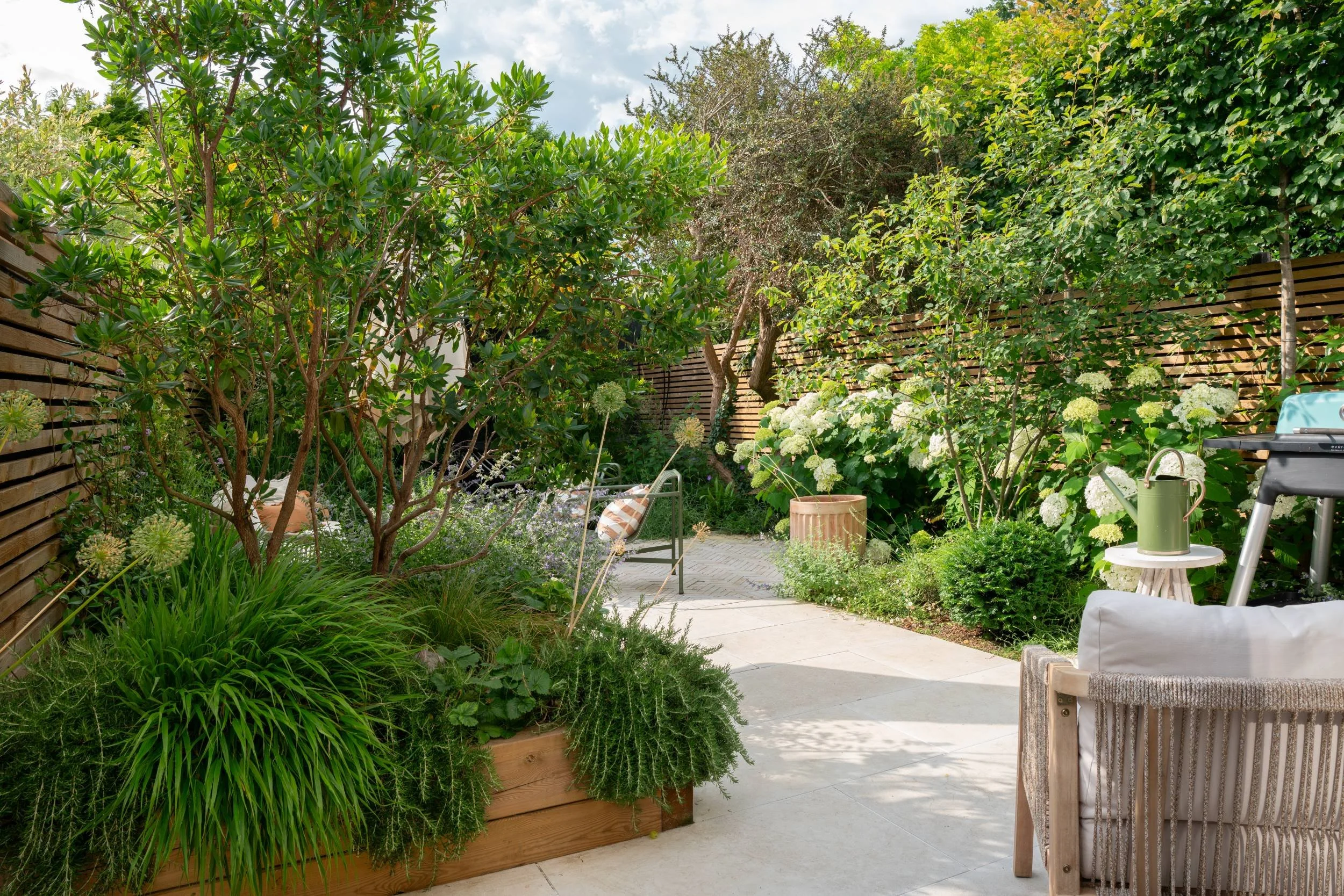 Stepping-stone path leading through dense planting from front to back of a Cobham garden