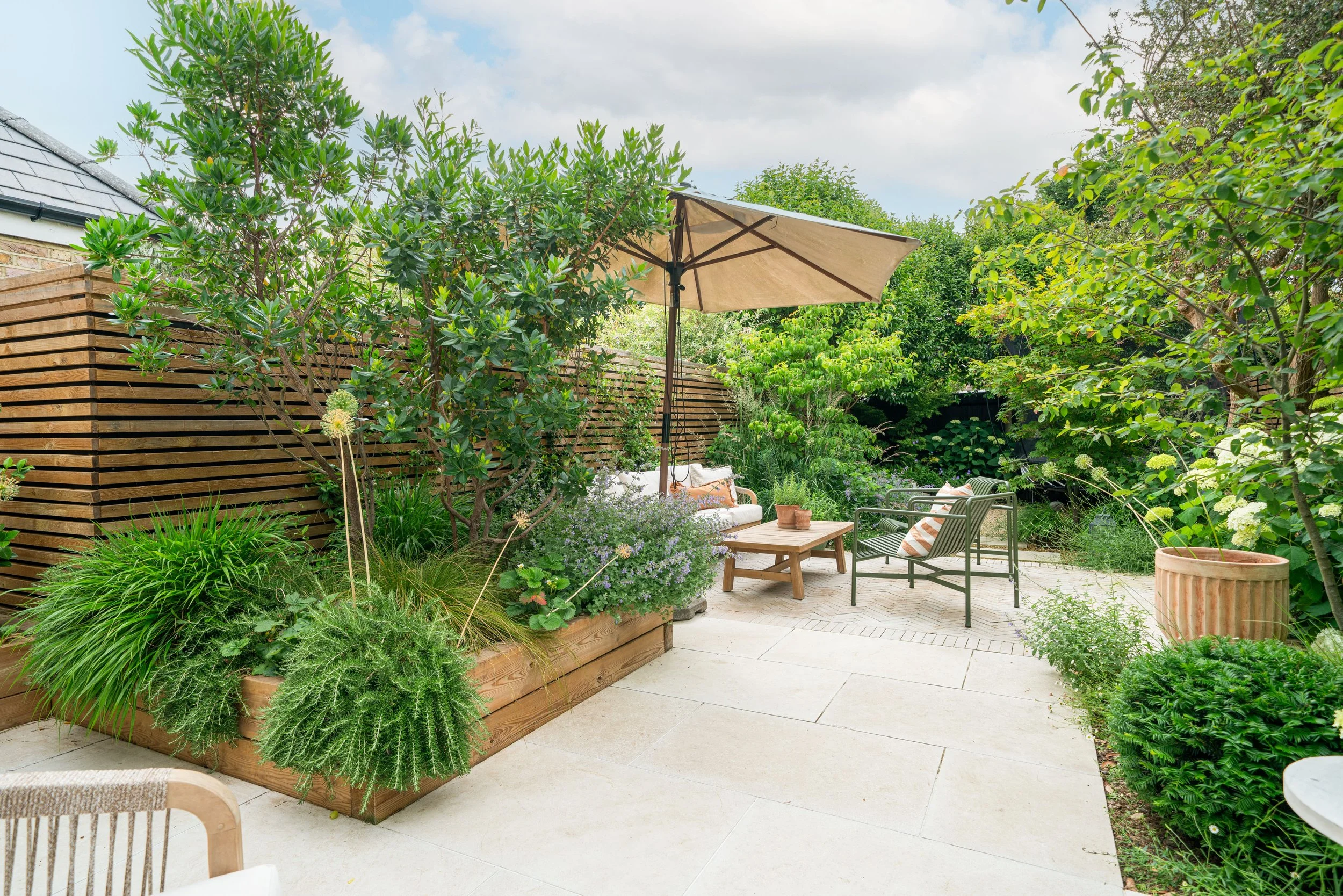 Courtyard garden in Cobham with limestone paving, slatted screens and raised Corten-edged beds designed by Paul Studholme