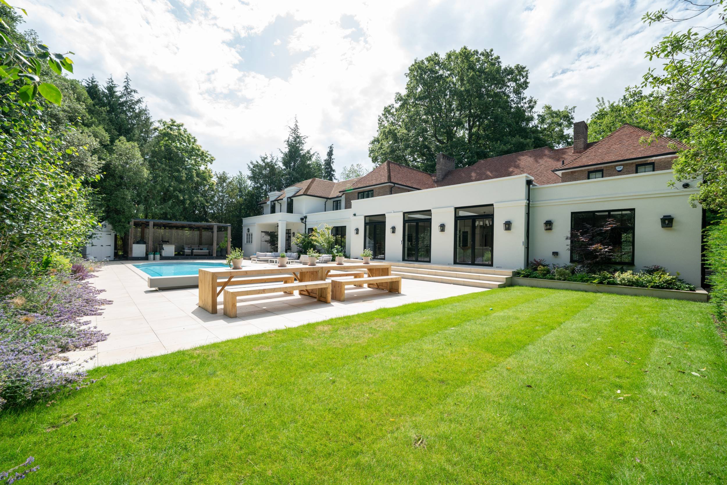 Lawn, pool terrace and house of a family garden in Weybridge designed by The Plant Hunter.