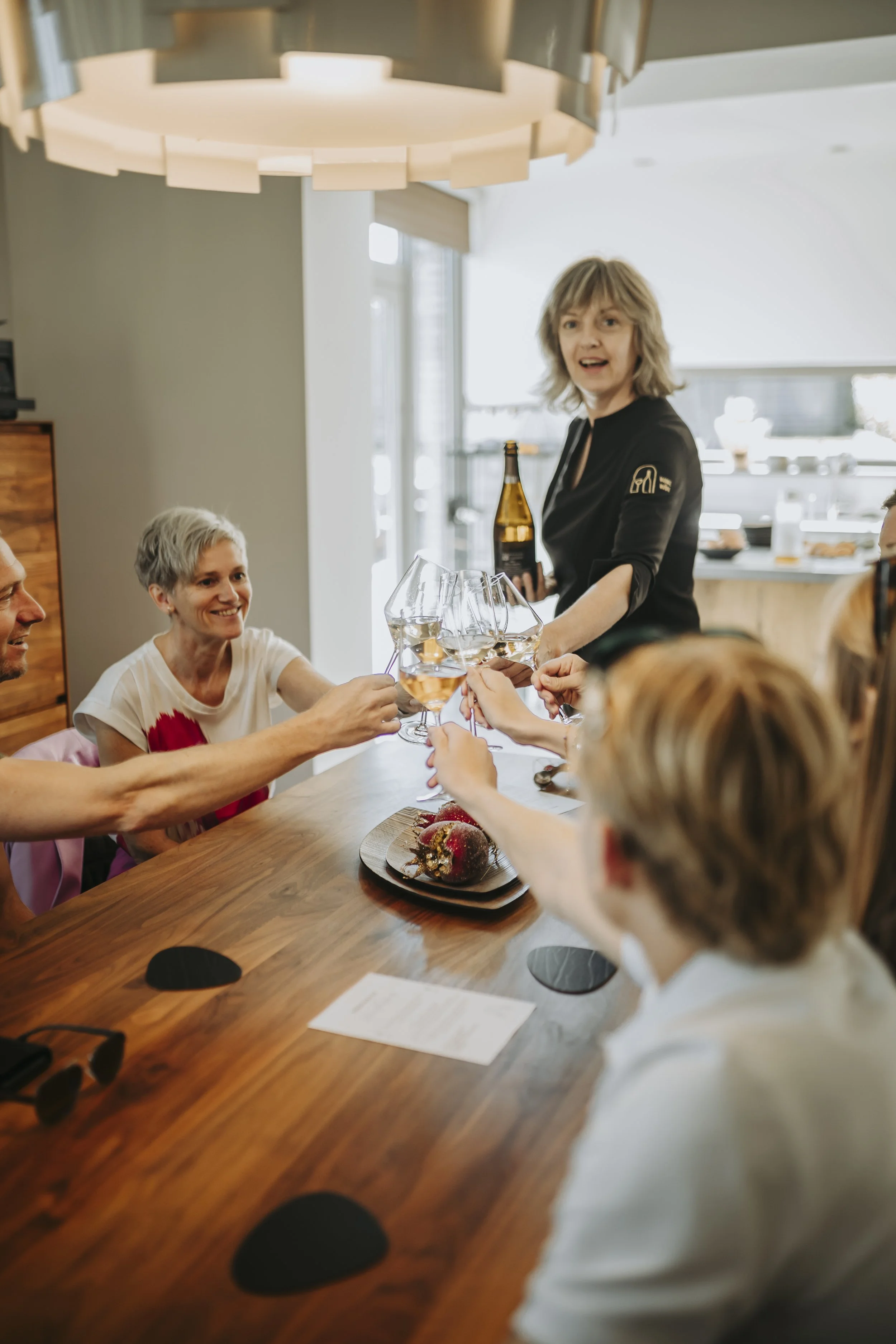 Mensen vieren samen in een gezellige eetkamer, toosten met wijn, terwijl een vrouw een drankje vasthoudt.