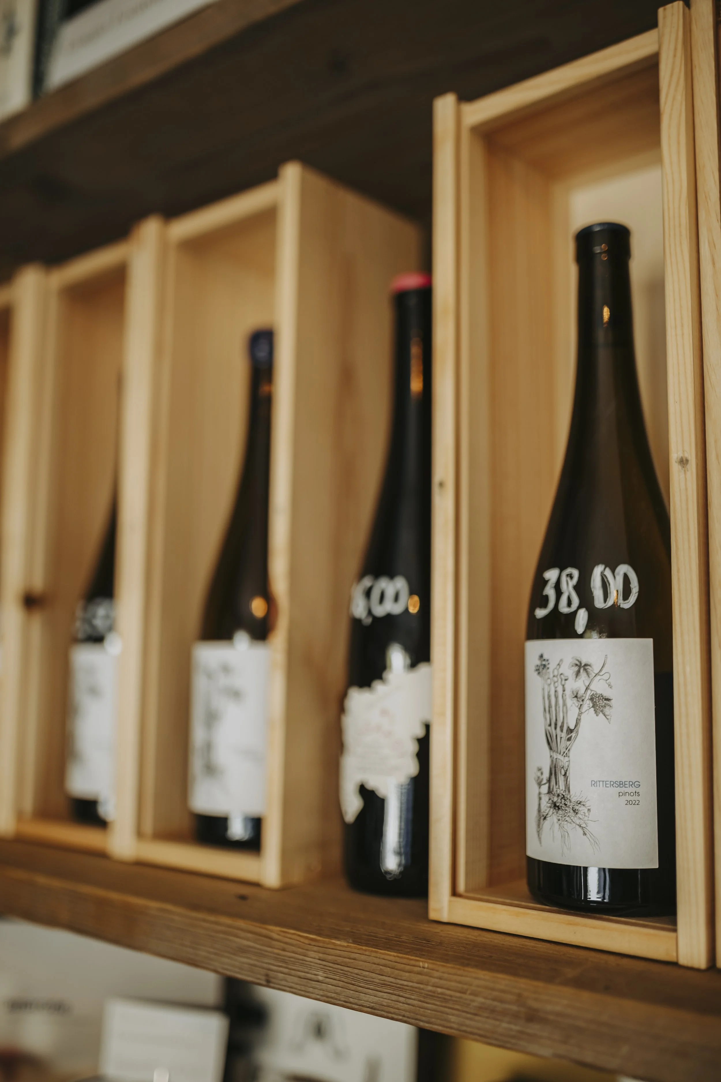 Flessen wijn in houten kisten op een plank.