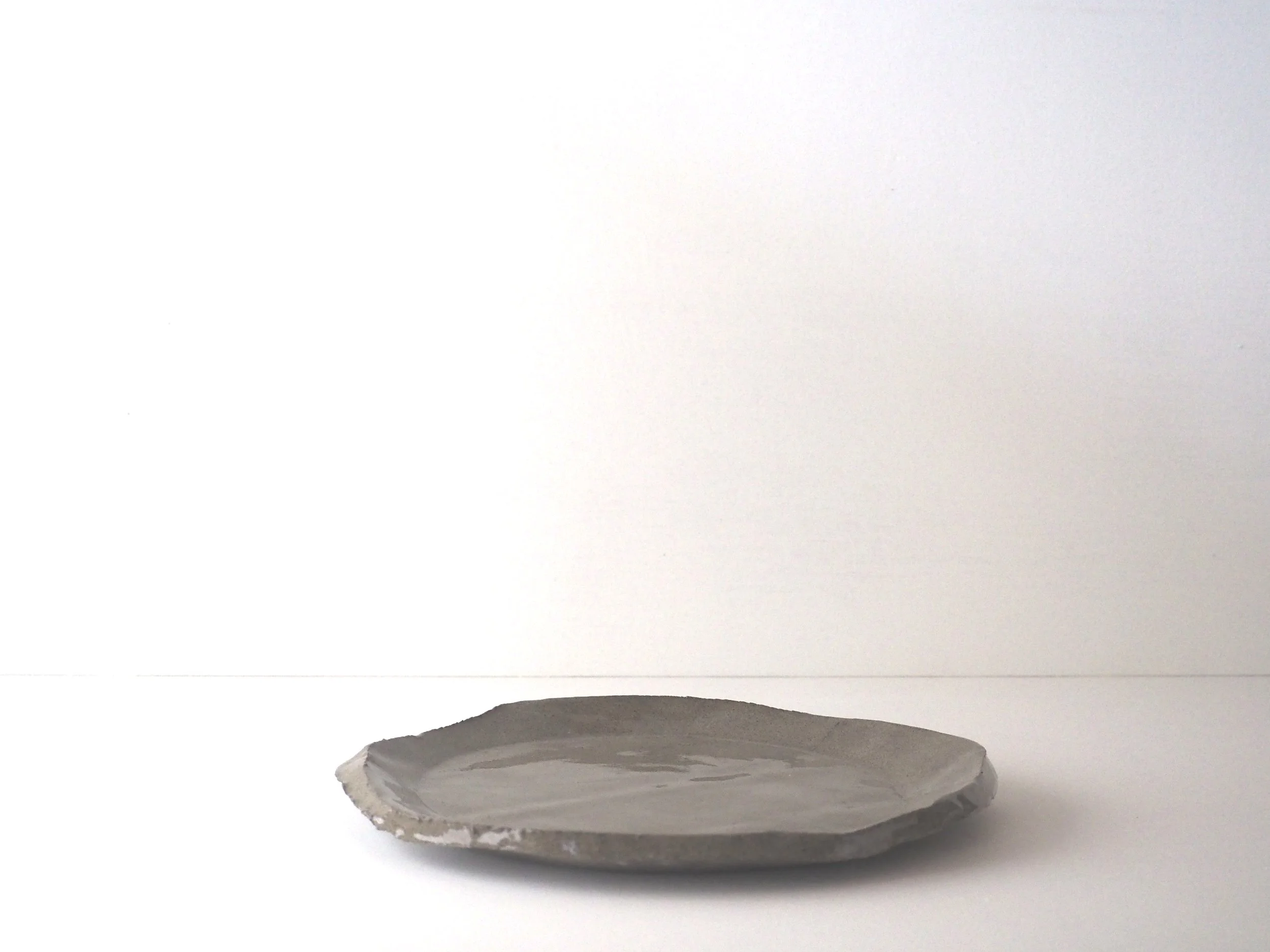 Gray ceramic plate lying flat on a white surface in front of a plain white background.