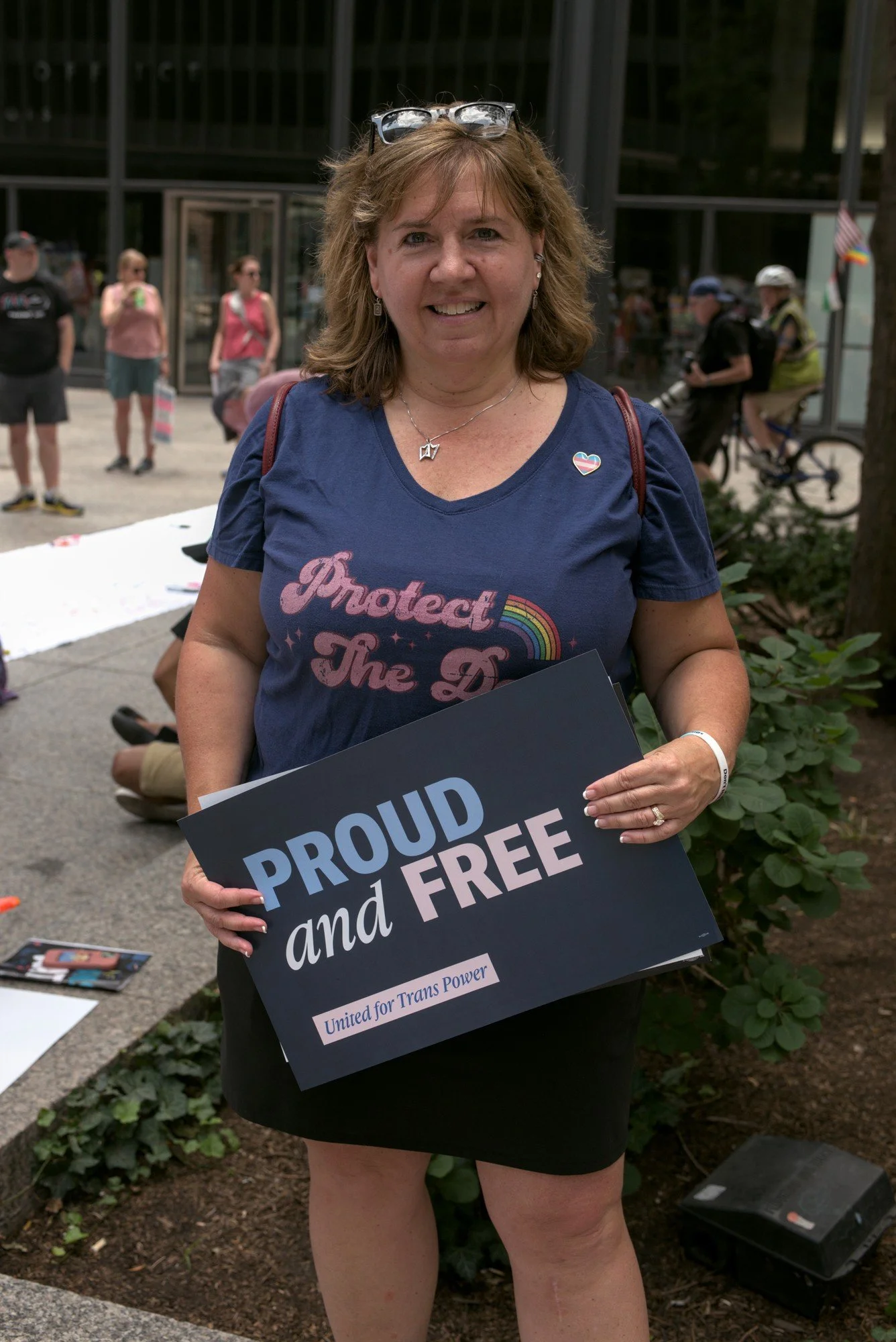   A portrait of Kathy, a blond haired woman holding a sign that reads 