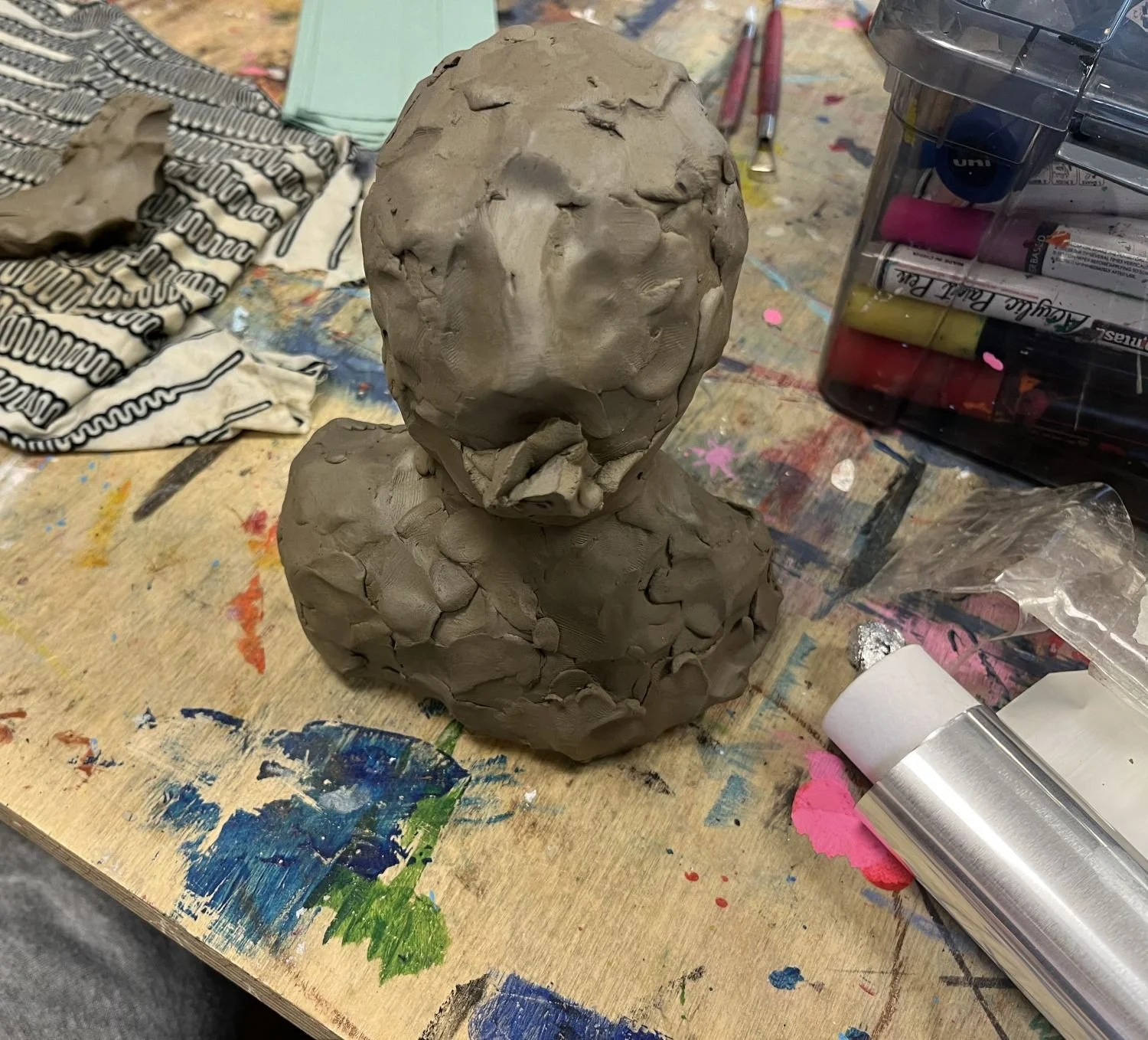 An unfinished clay bust without a face, heavily textured with finger marks