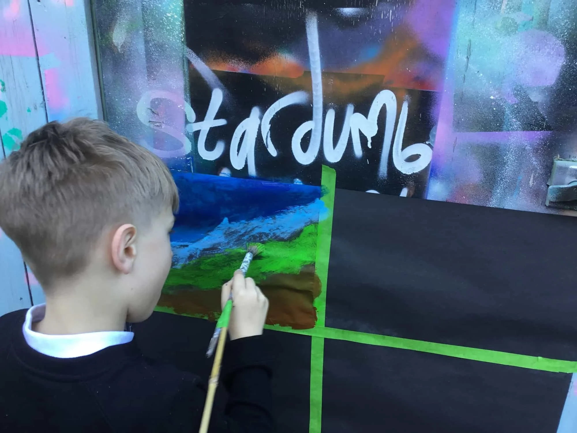 Young person painting an earthy landscape scene in our courtyard