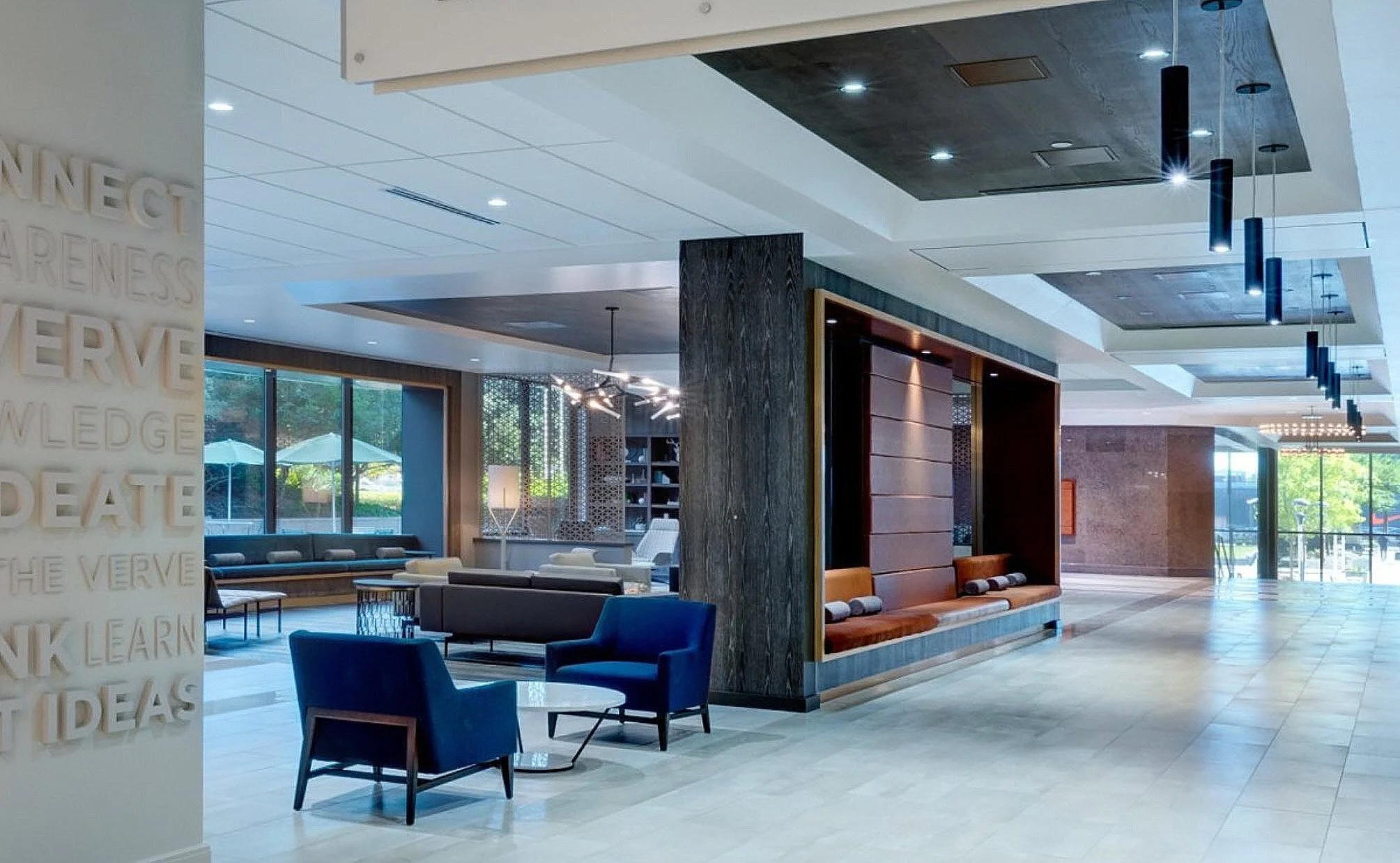 Modern hotel lobby with seating areas, large windows, and contemporary lighting fixtures.