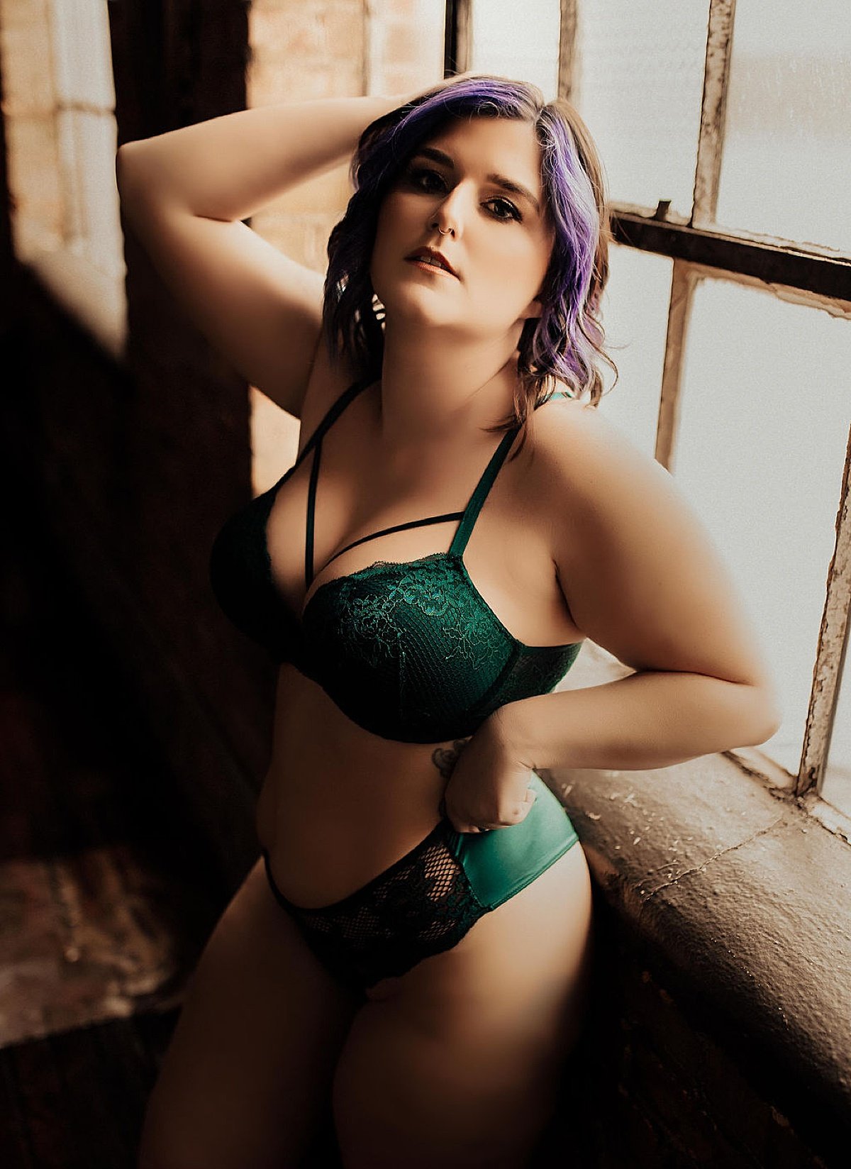  woman in dark green lace and satin lingerie poses for fort wayne boudoir photographer 