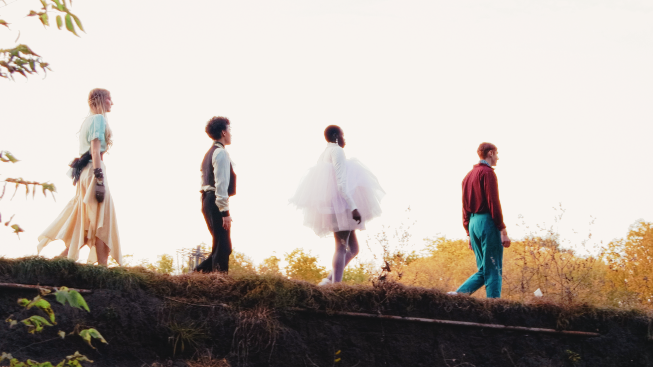Five people walking in a line outdoors during sunset, with trees and clear sky in the background in Ames, Iowa.
