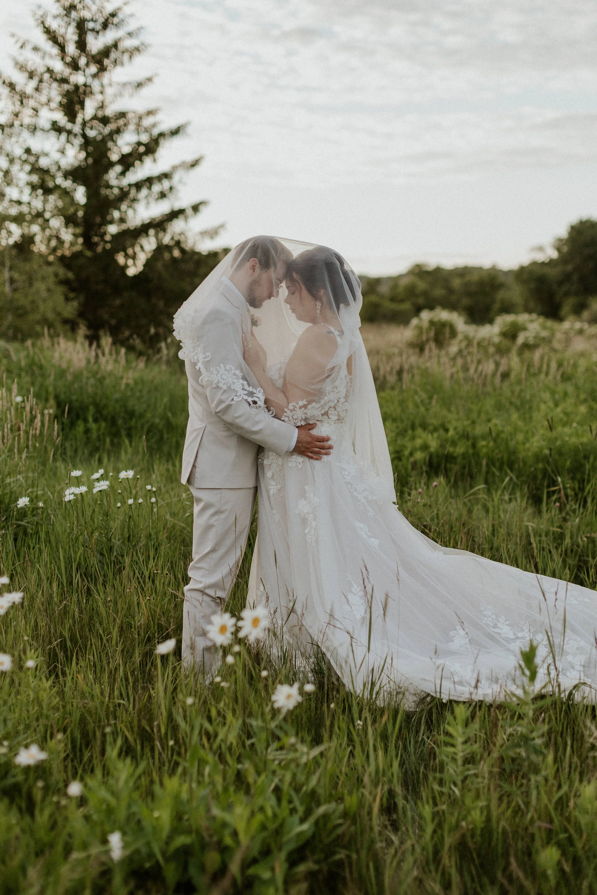 young bridal couple touching heads together under her bridal veil