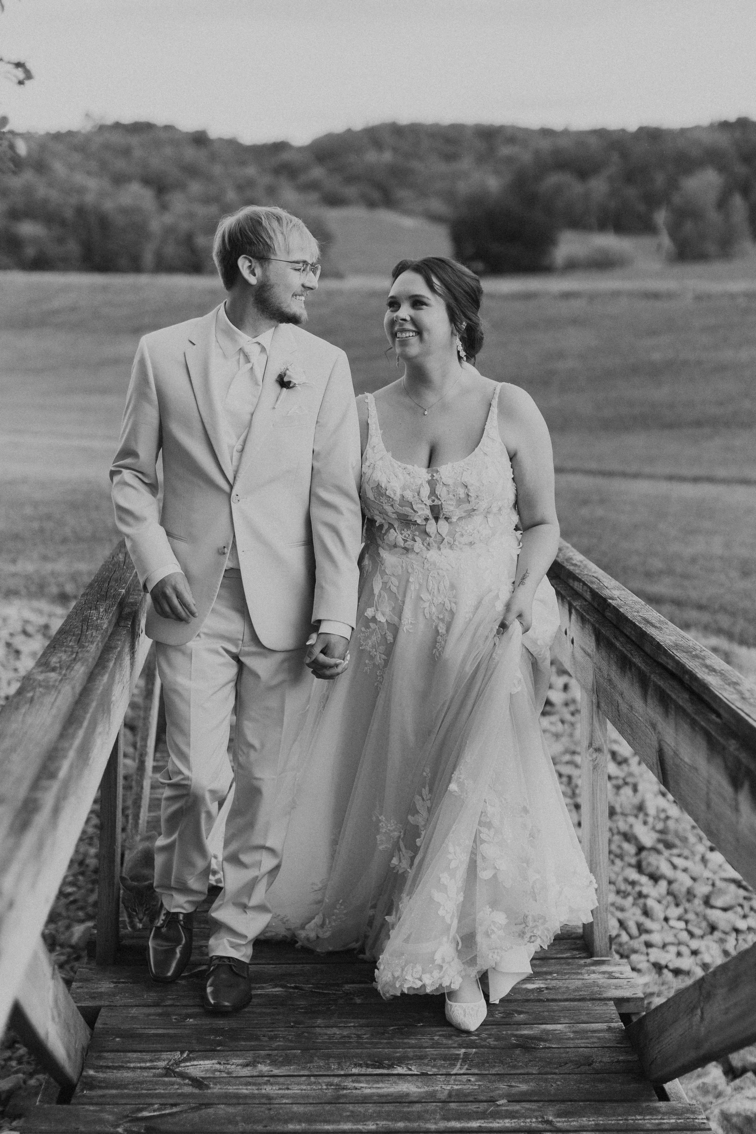 eloping couple smiling and holding hands walking across bridge
