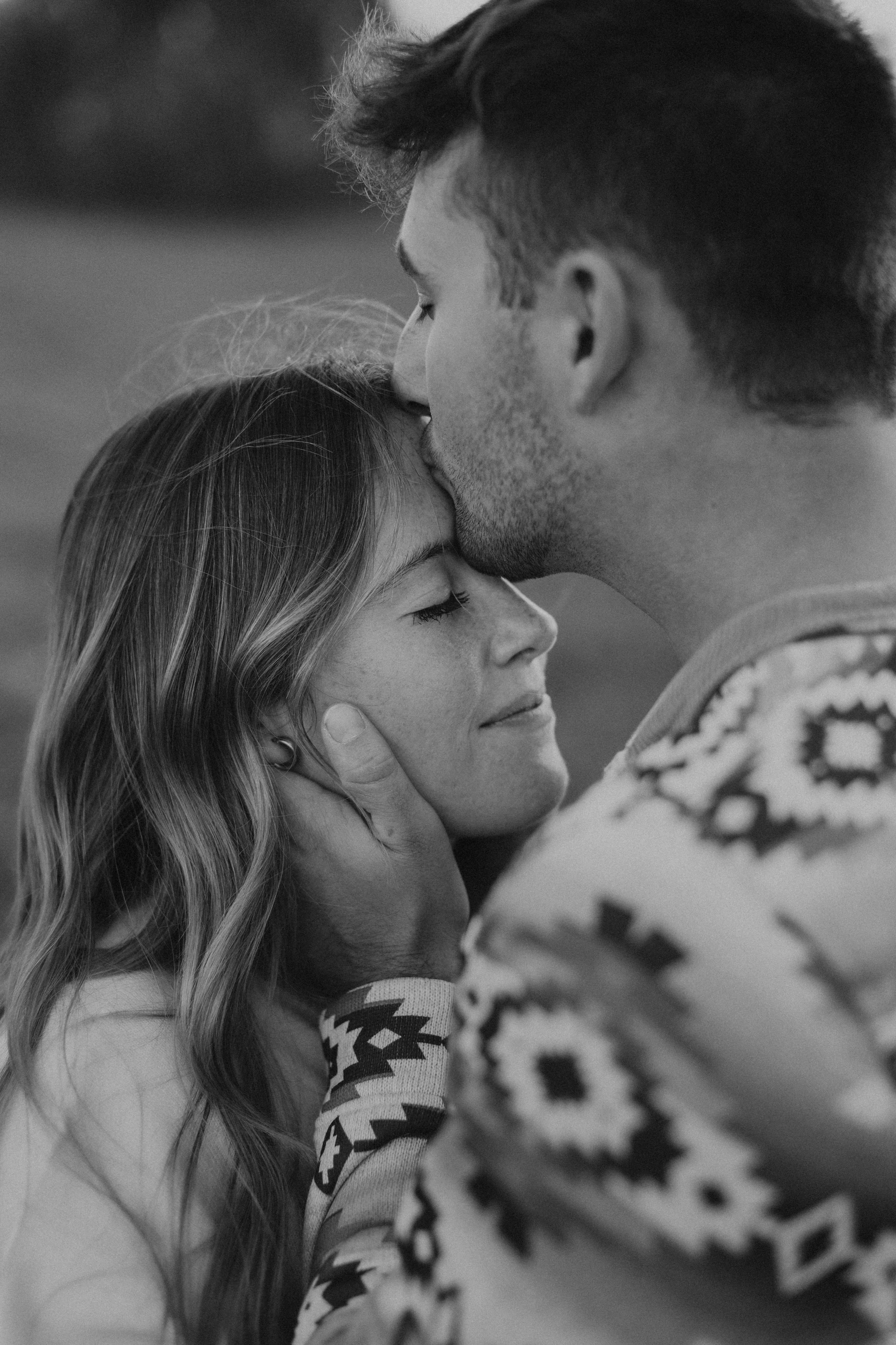 close up of man holding women's face and kissing her forehead