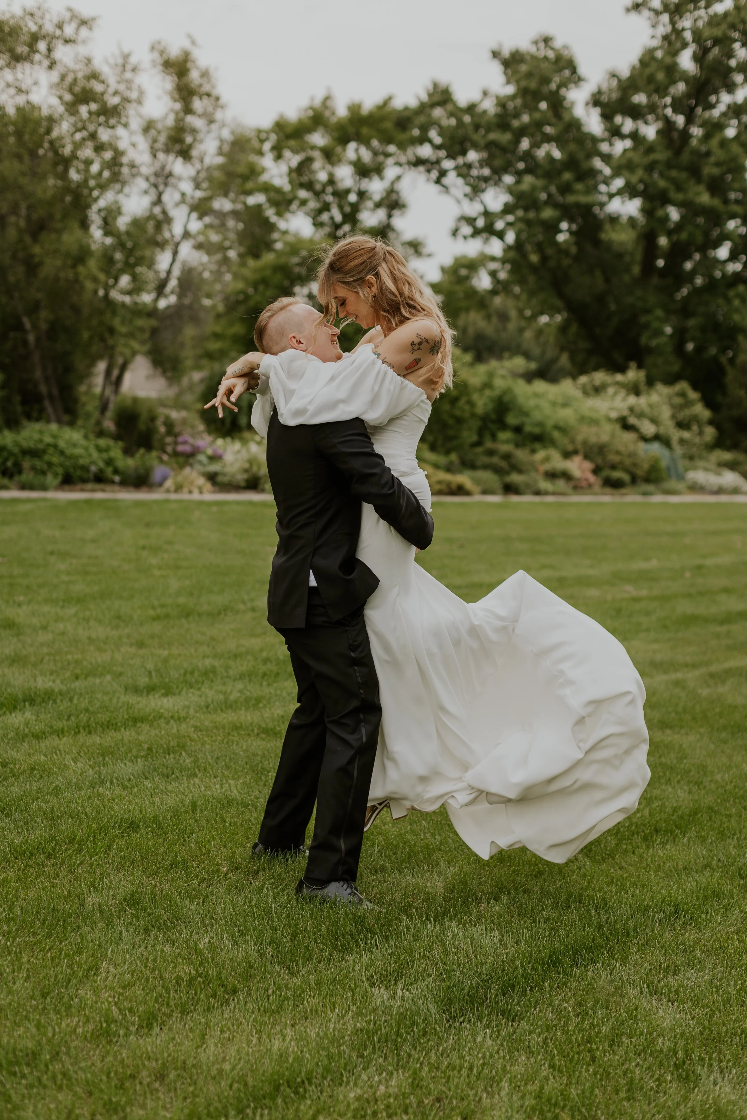 groom picking up bride and spinning here in bright grassy field