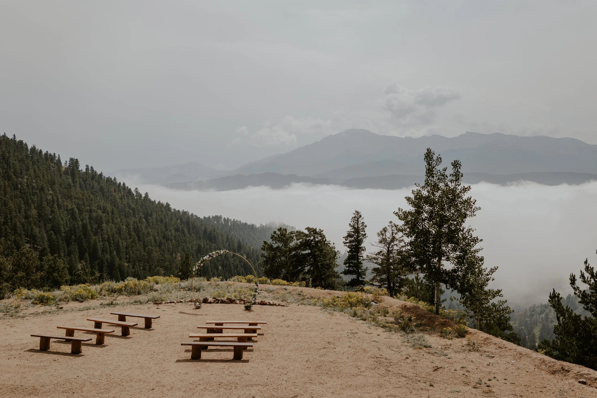 view of intimate wedding ceremony set up on mountain in colorado with fog rolling in