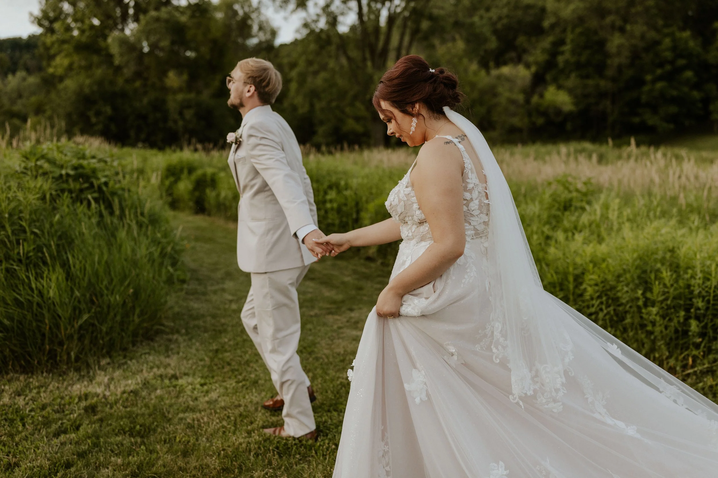 eloping couple walking through field in bridal attire