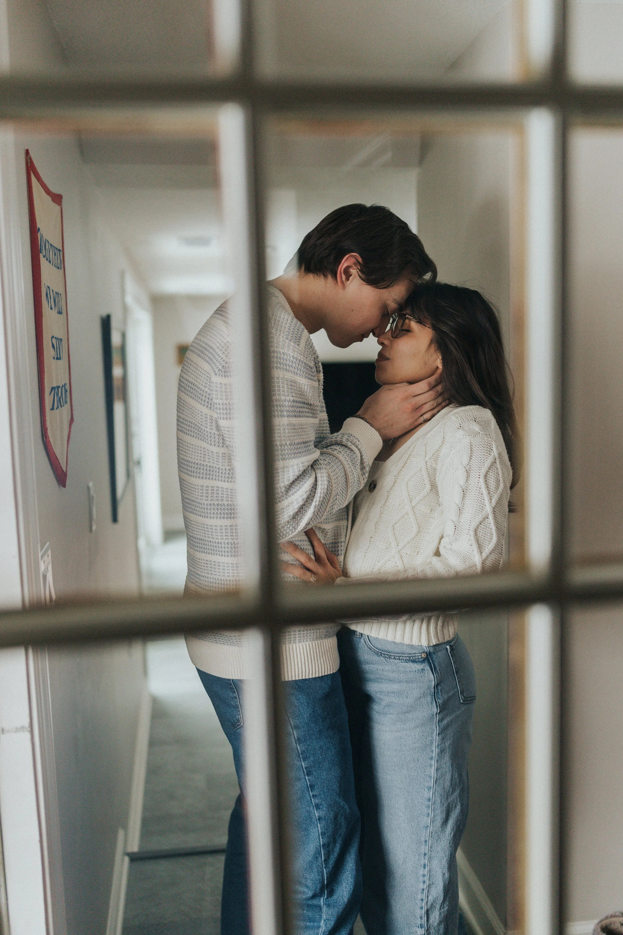 couple embracing in hallway through a window